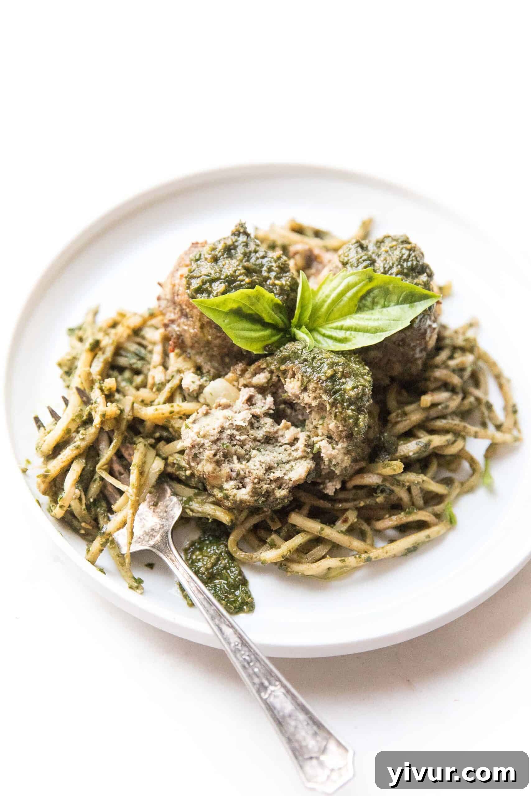 Pesto meatballs arranged beautifully on a bed of pesto-infused hearts of palm low-carb noodles.