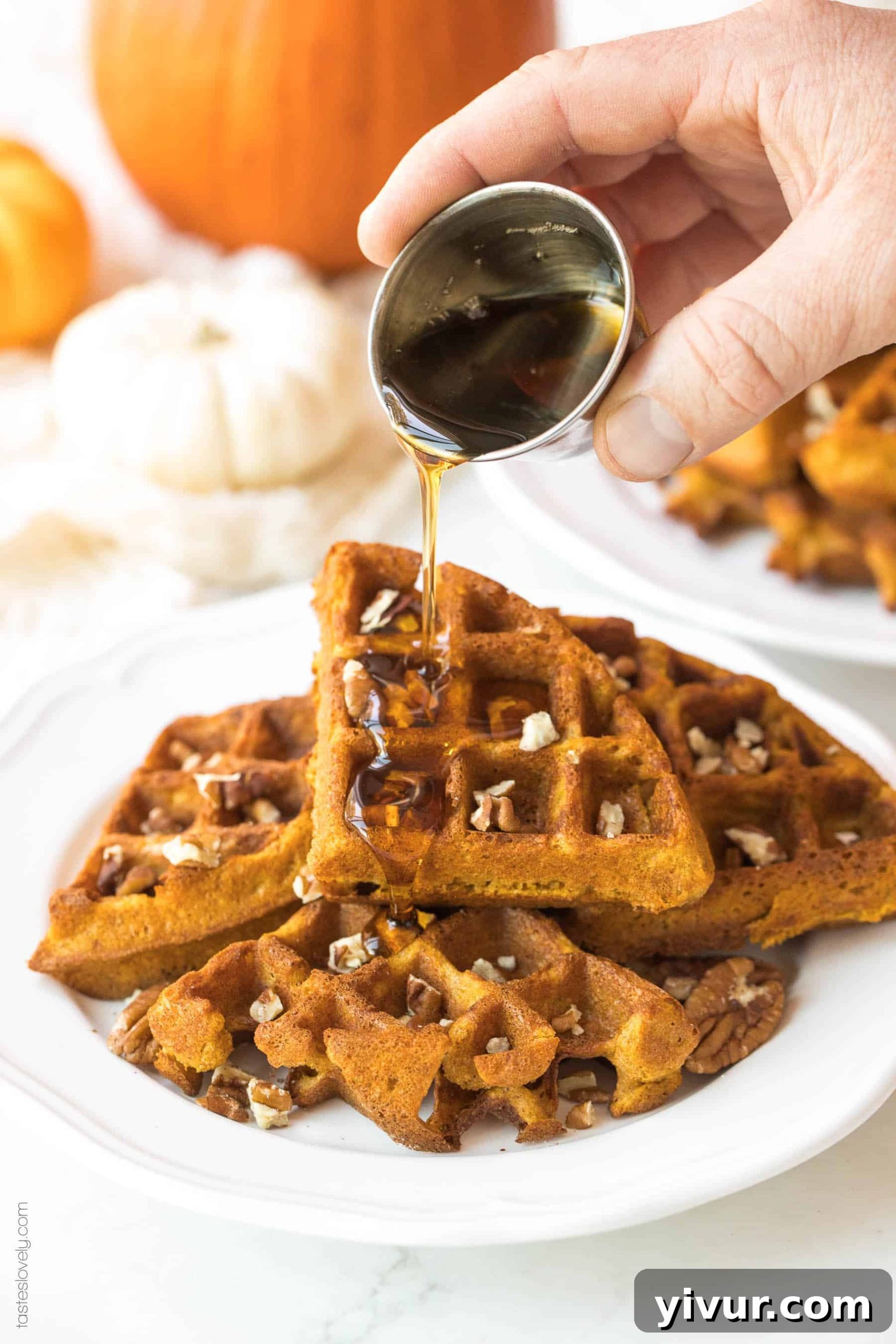 Syrup being poured over a stack of golden crispy paleo pumpkin waffles
