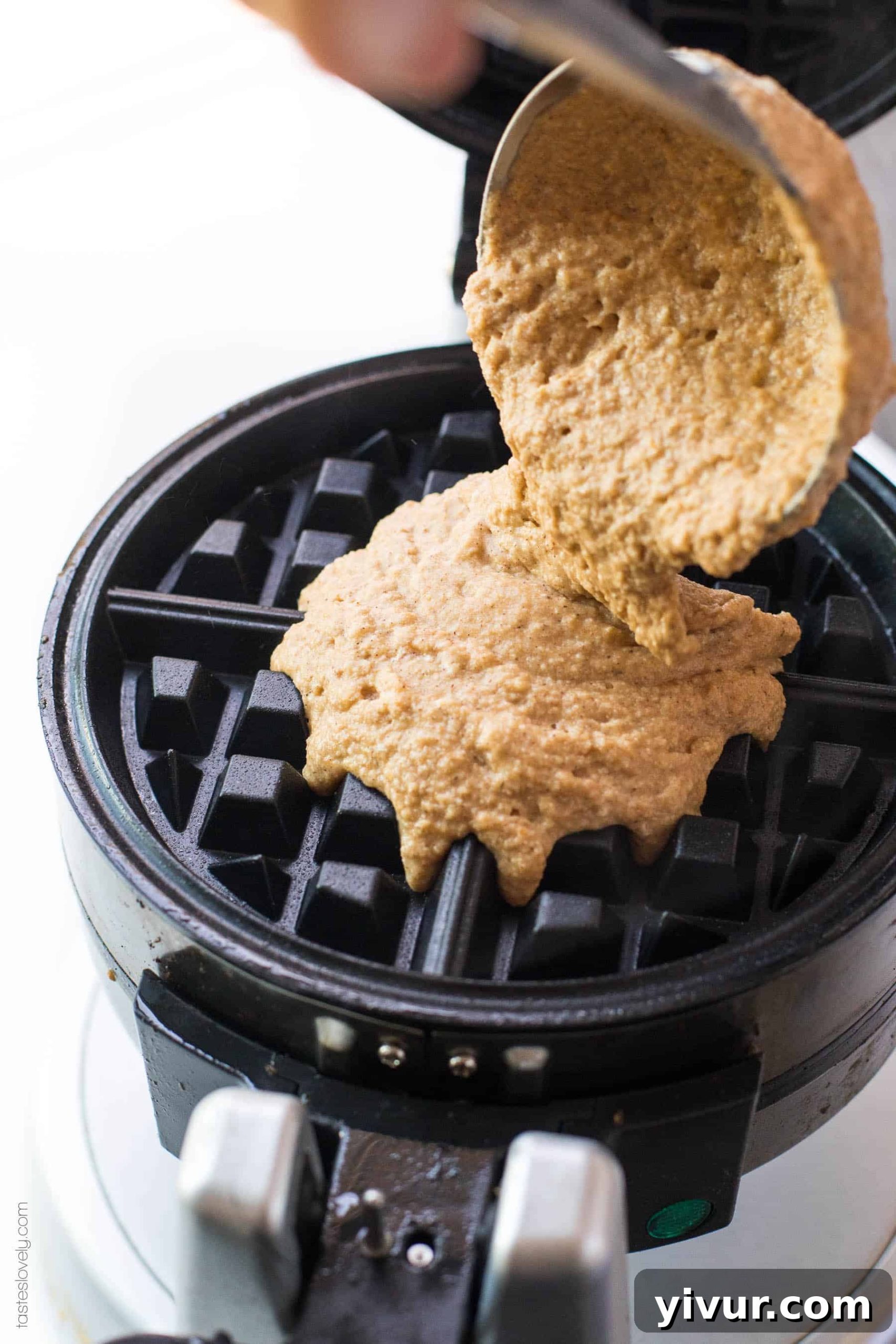 Pumpkin waffle batter being carefully poured into a hot waffle iron
