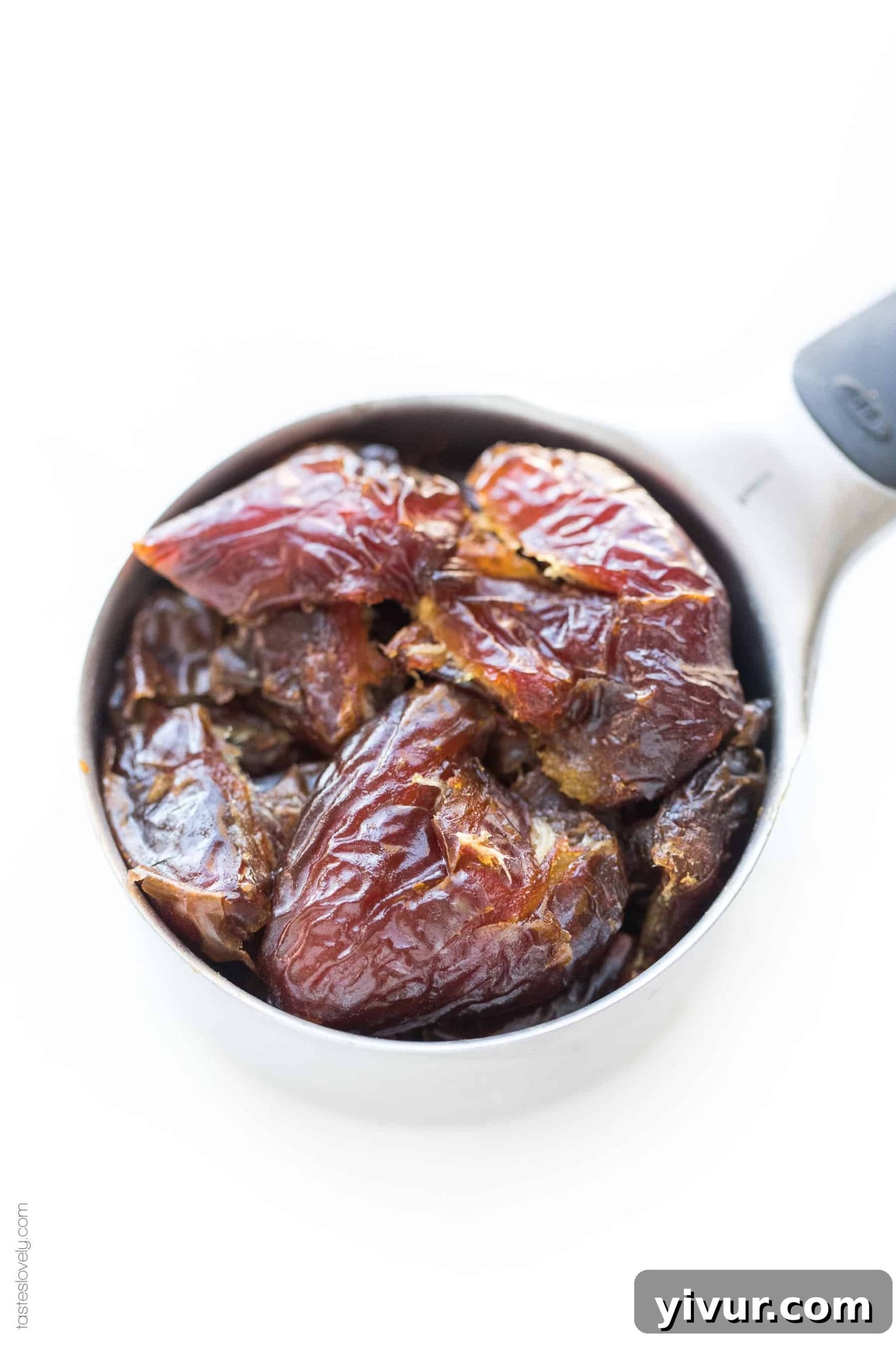A measuring cup filled with pitted Medjool dates, ready for blending into a healthy sugar substitute.