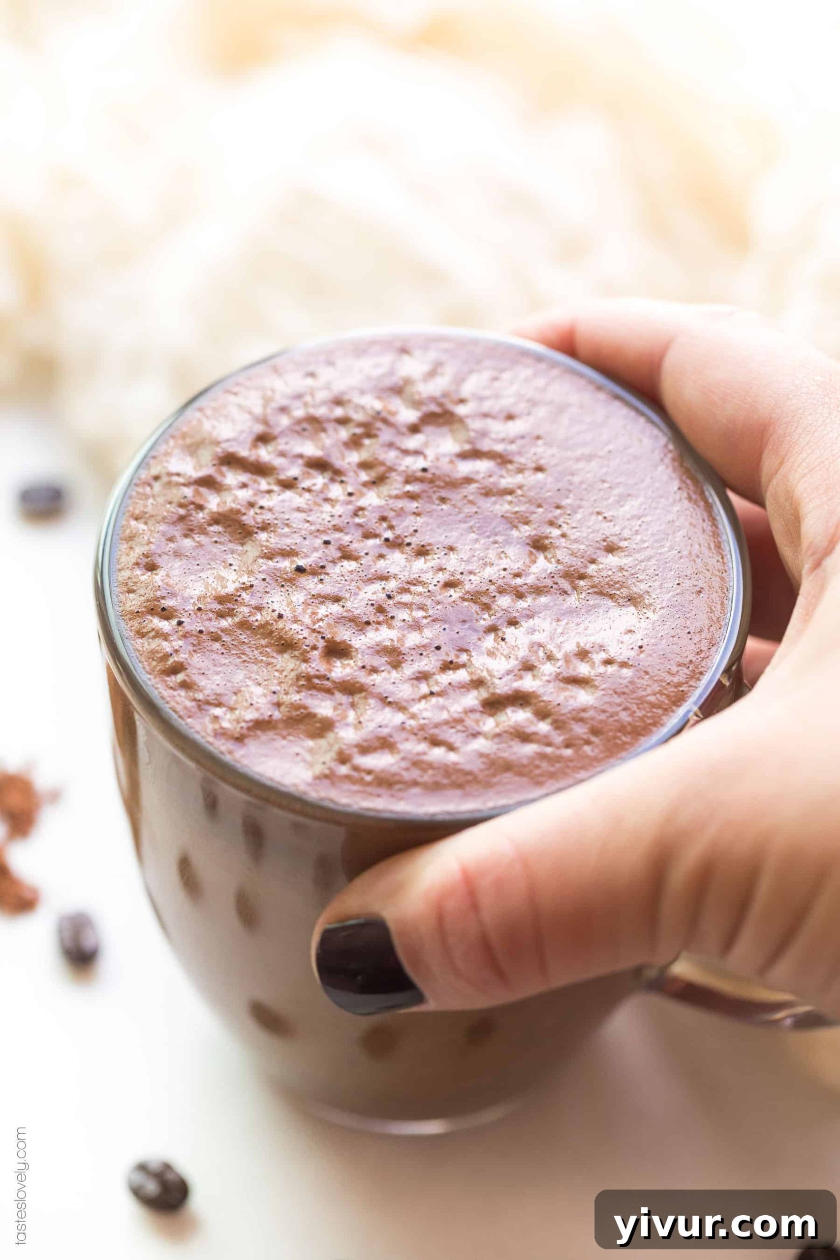 A hand holding a mocha in a clear glass, a delicious and healthy clean eating coffee drink