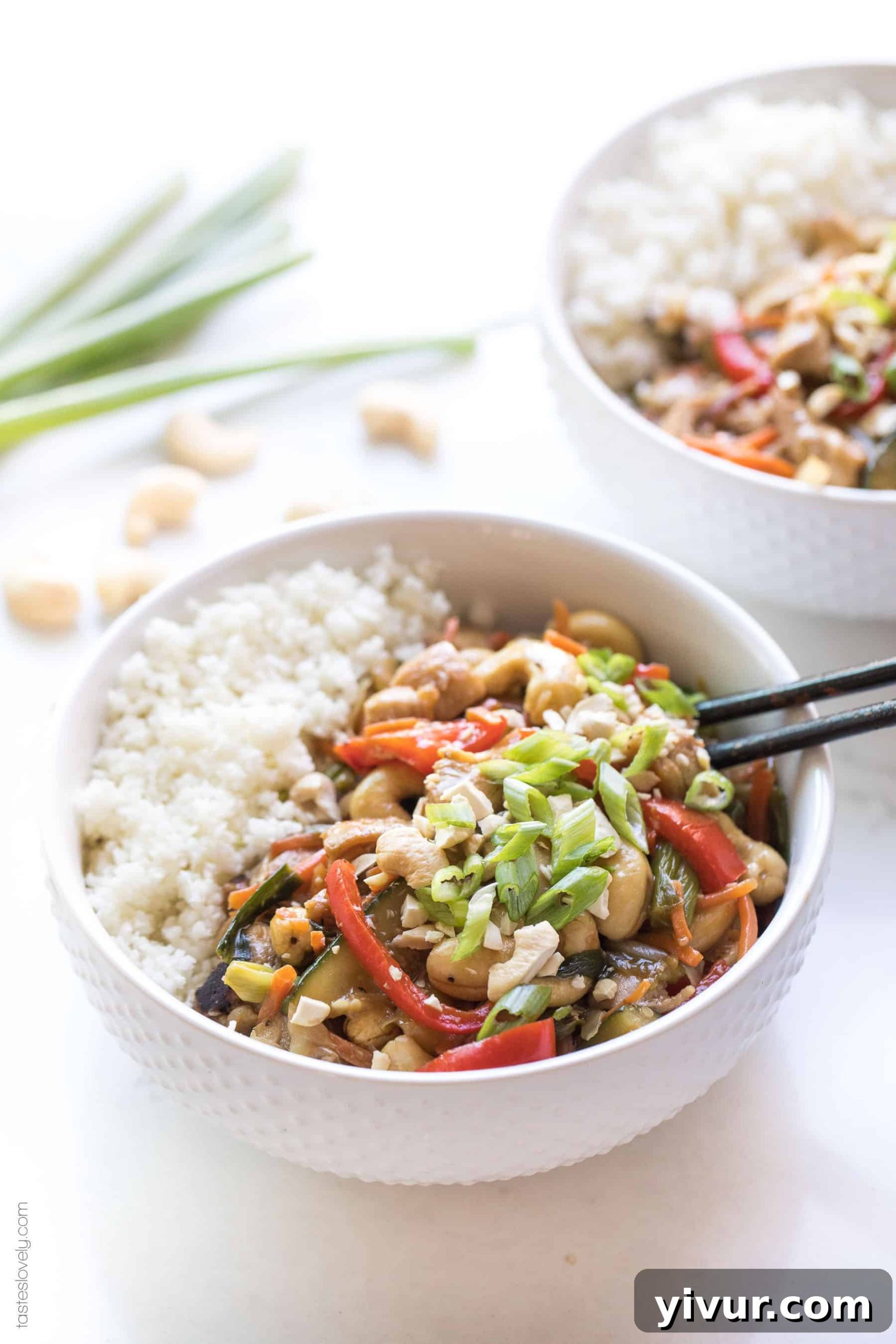 a white bowl with chicken stir fry, cauliflower rice and chopsticks