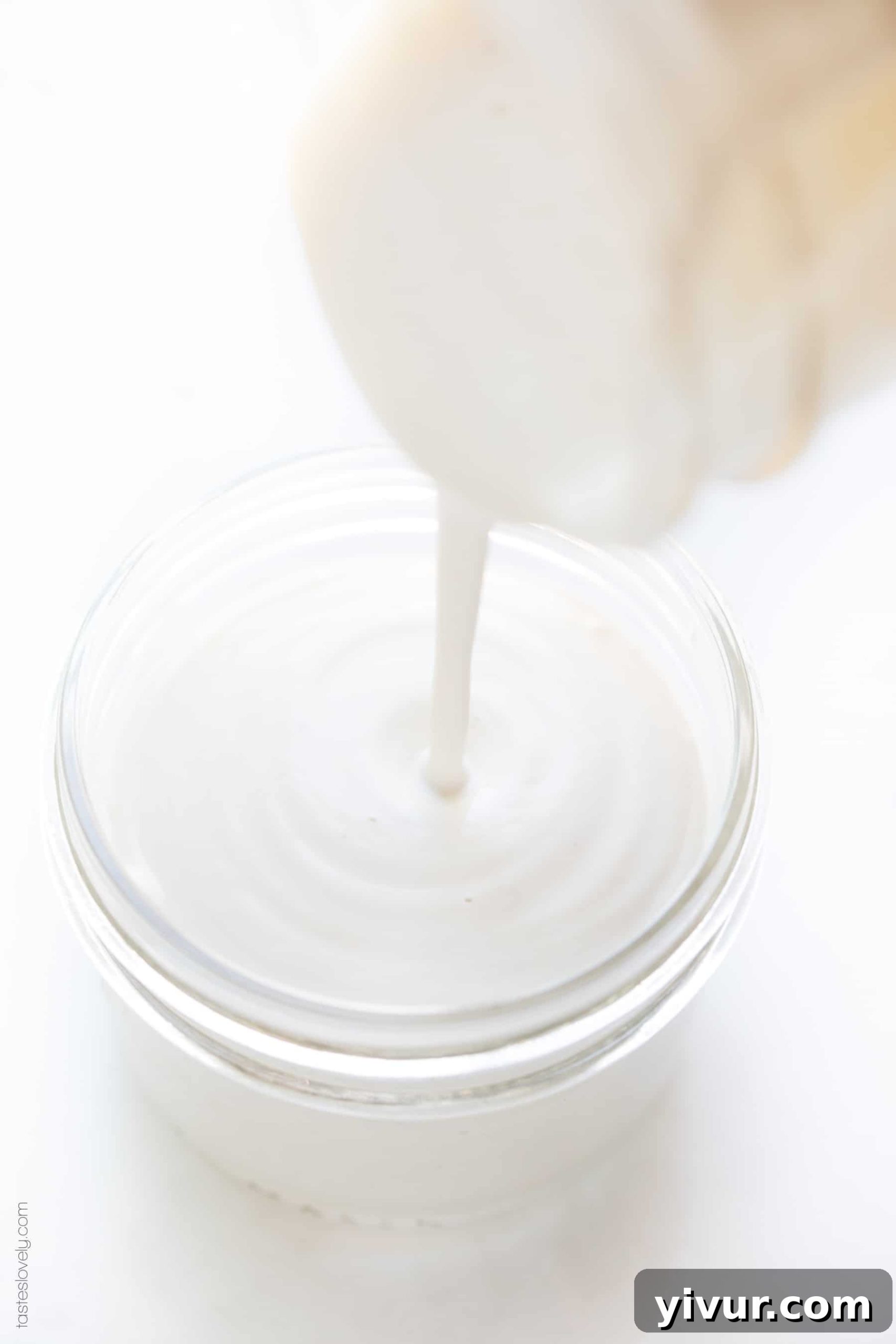 Pouring freshly blended cashew cream from a blender into a clear mason jar.