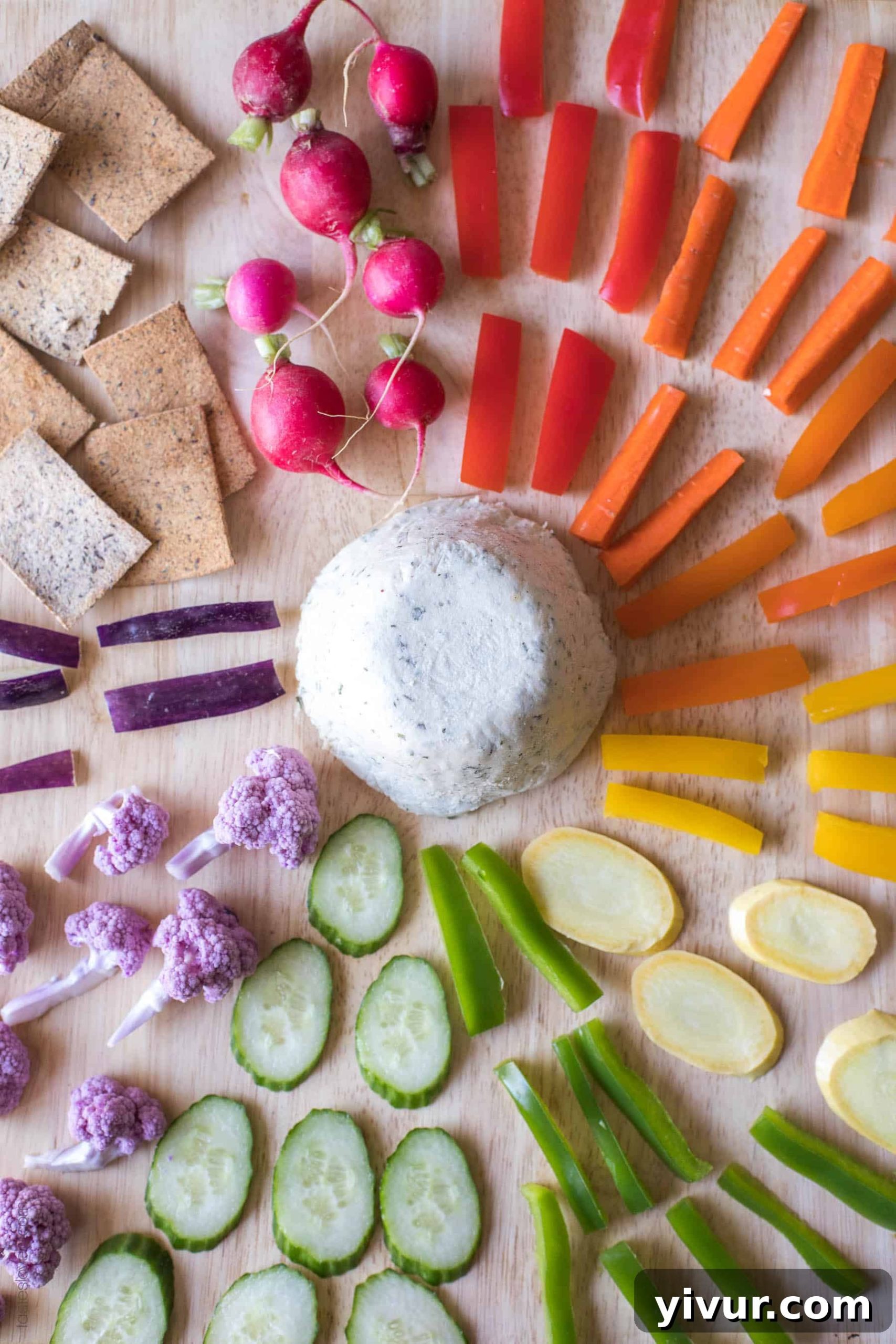 Colorful platter featuring Herbed Cashew Cheese surrounded by an assortment of vibrant rainbow vegetables, demonstrating healthy serving options.