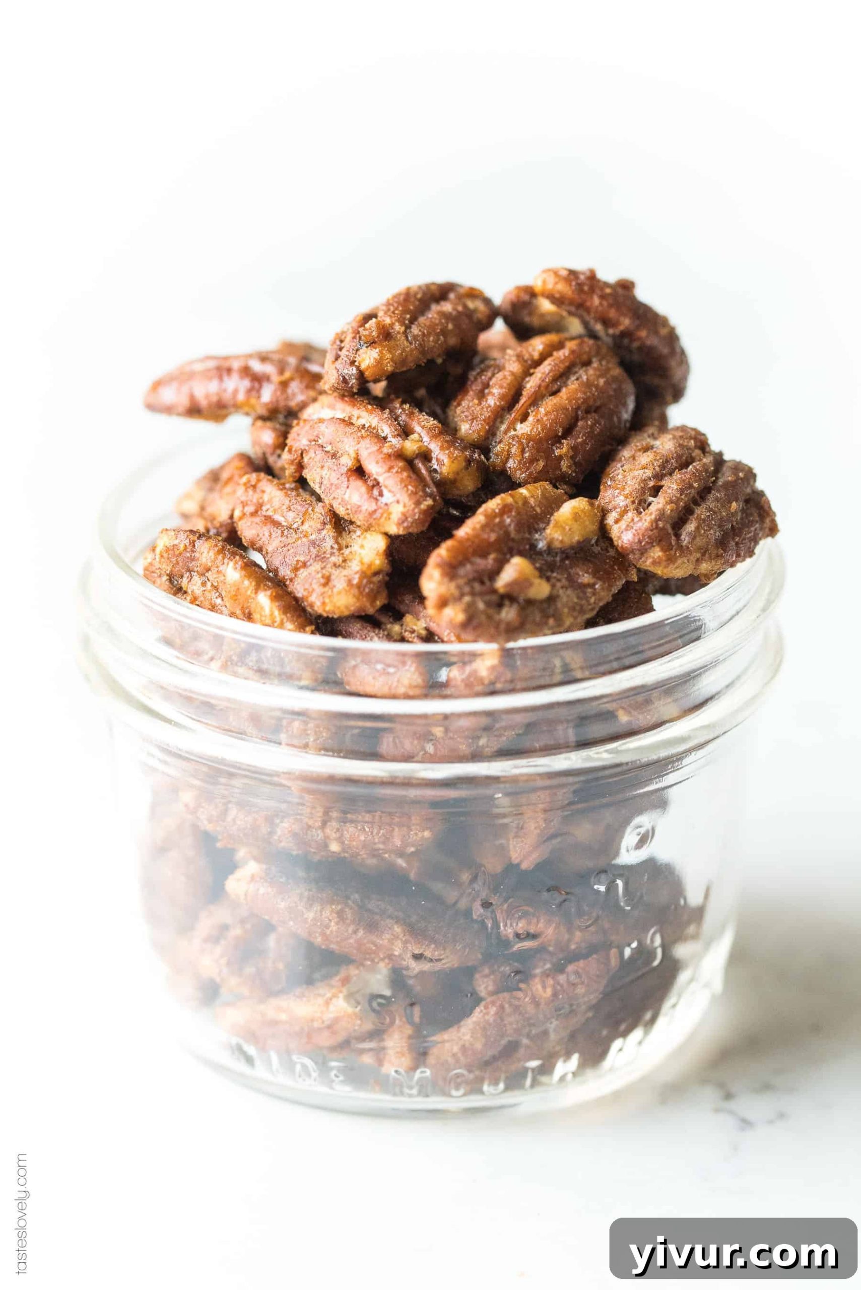 A small bowl of finished paleo candied pecans, perfectly roasted and golden, on a wooden surface.