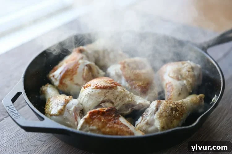 Rosemary Mustard Skillet Chicken simmering in a cast iron pan, just out of the oven