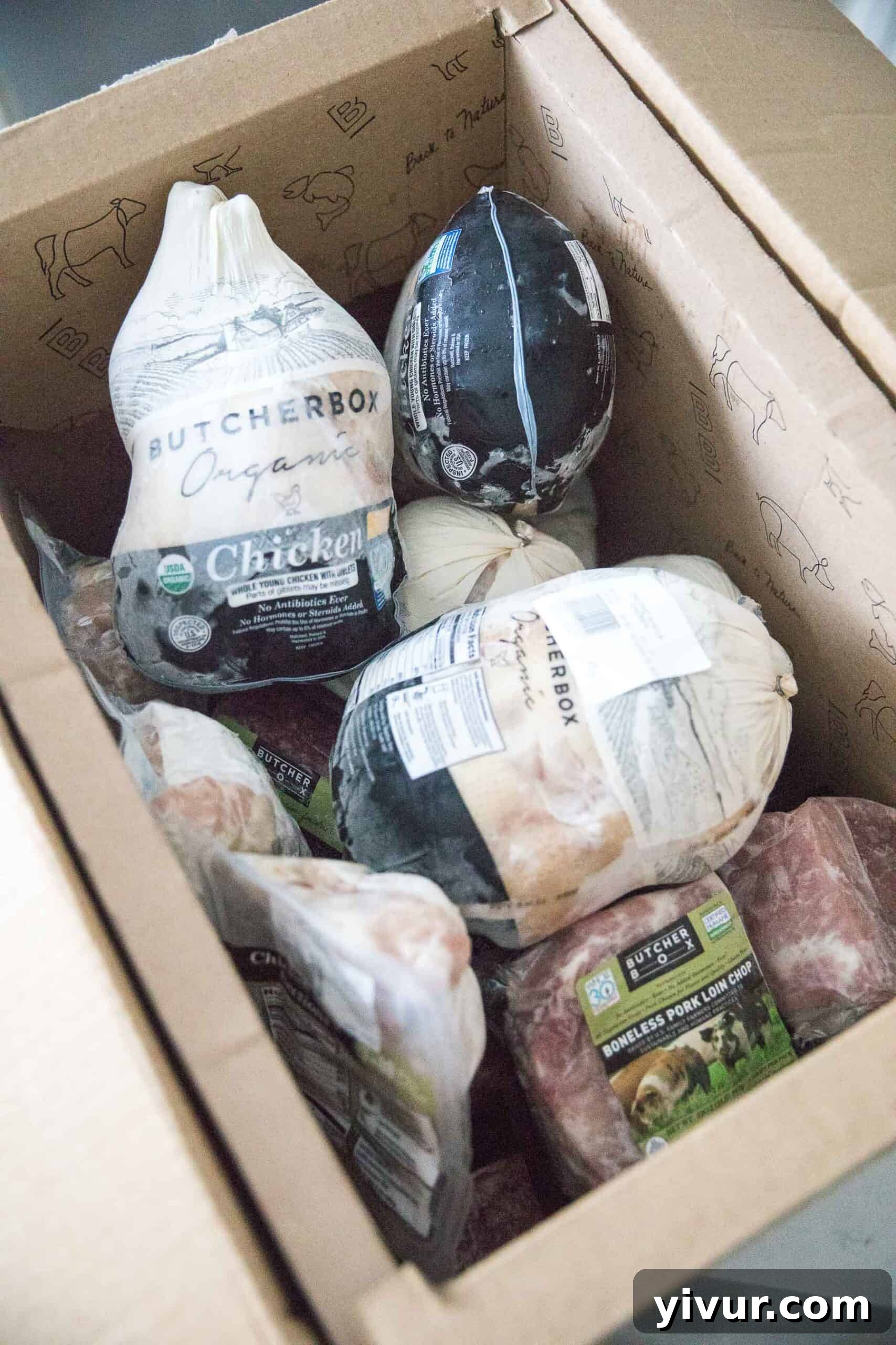A ButcherBox shipment opened to reveal perfectly frozen cuts of meat with dry ice still visible, ready for storage