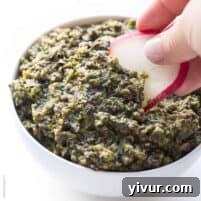 A small bowl of fresh olive tapenade, garnished with fresh herbs, ready to be served.