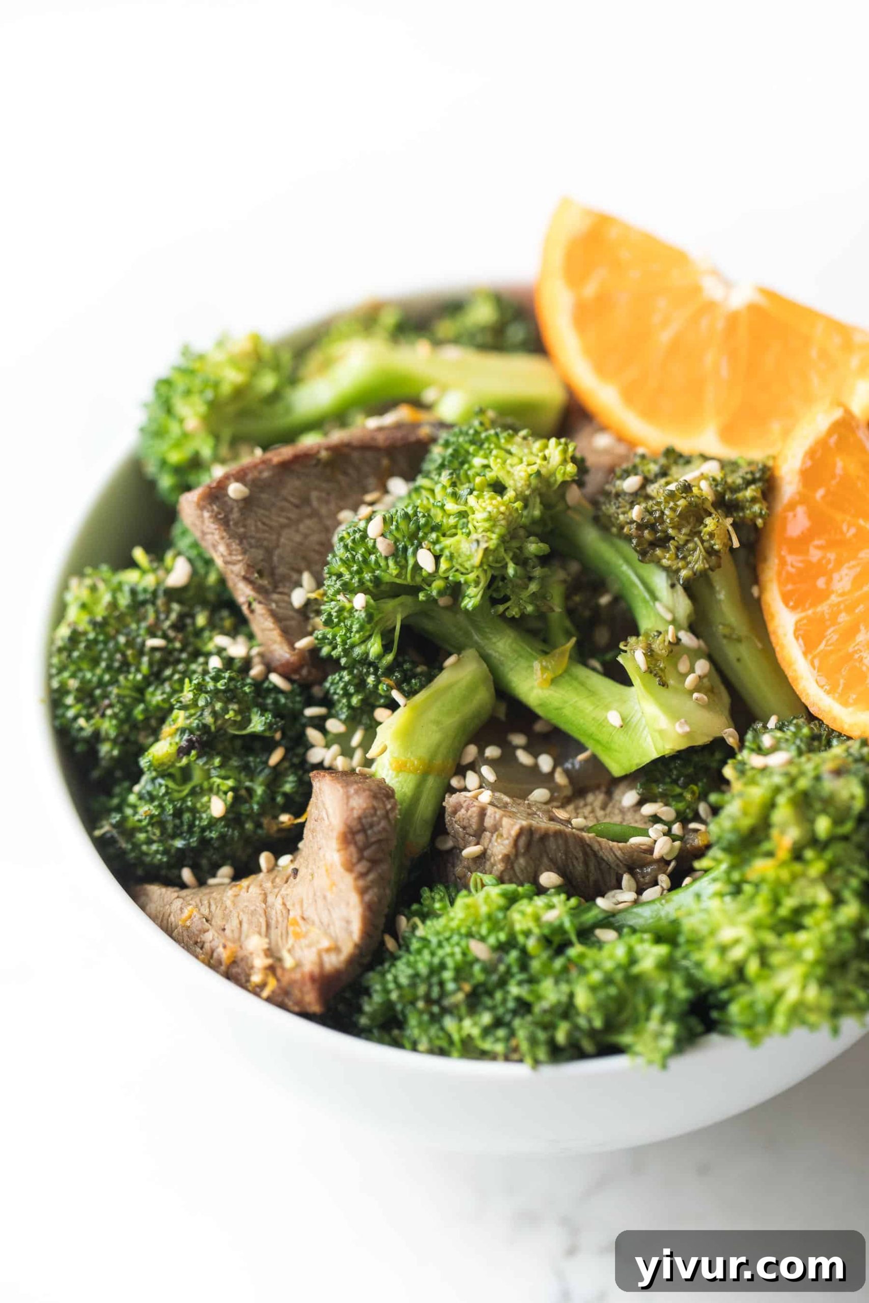orange broccoli beef in a white bowl