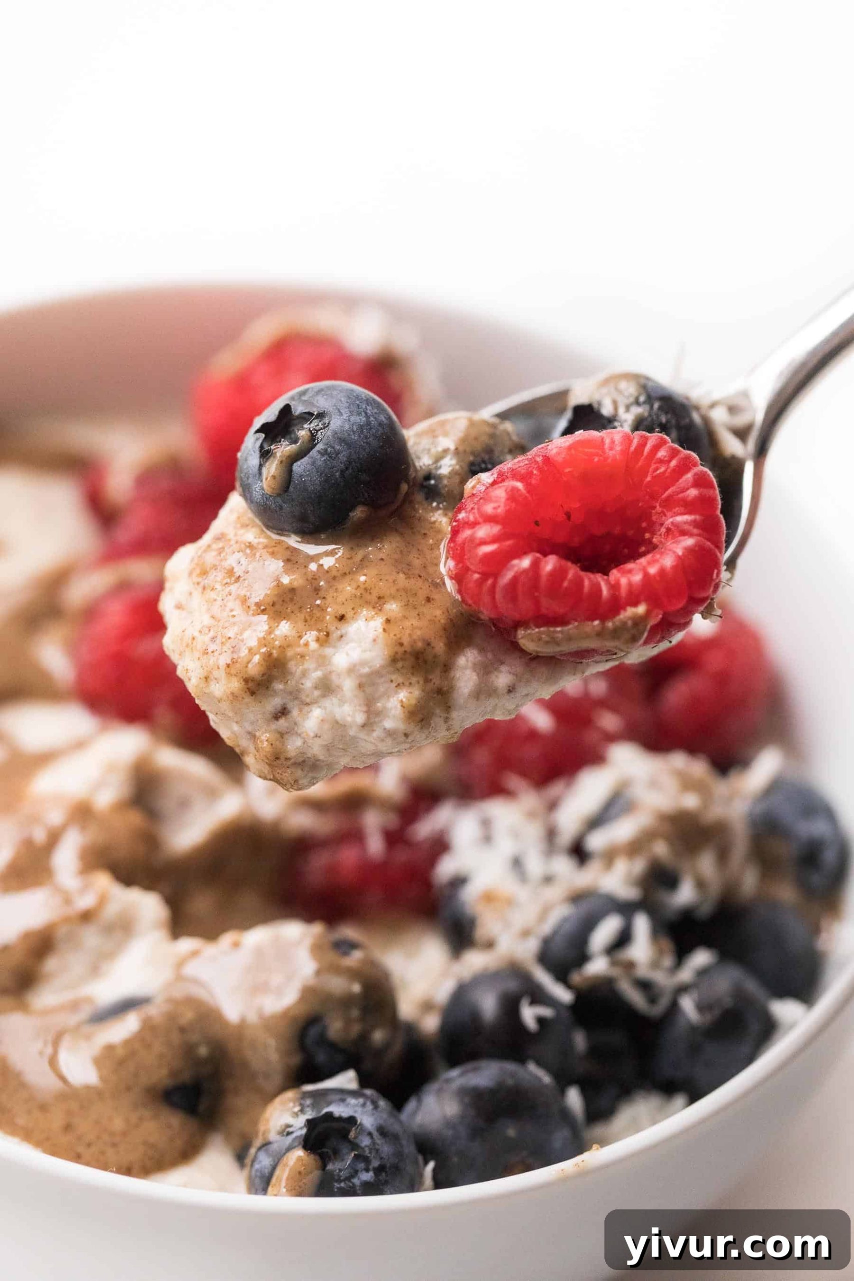 A spoon of healthy almond pulp breakfast porridge topped with fresh berries and rich nut butter, ready to be enjoyed as a paleo and whole30 meal.