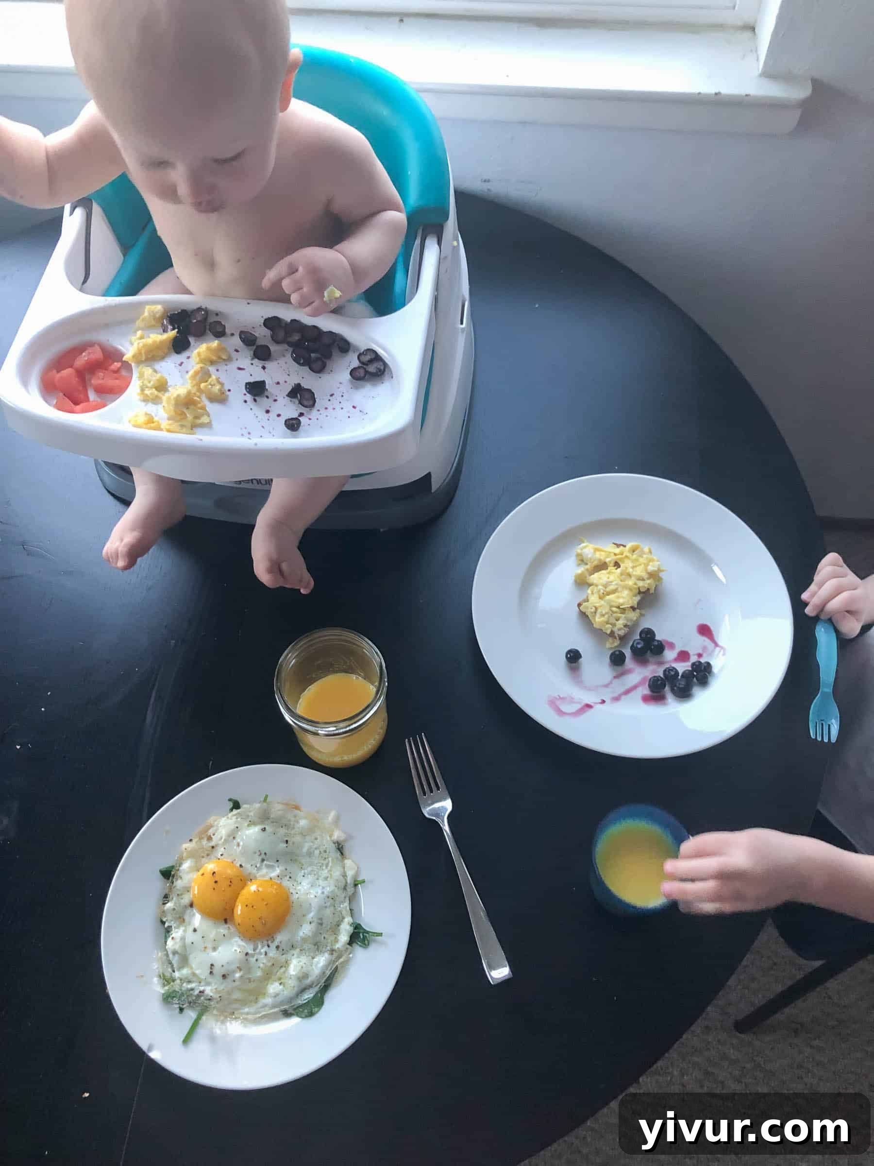 A busy morning scene: Mom diligently preparing a nutritious breakfast in the kitchen, reflecting a commitment to healthy eating, while her children are happily playing nearby, illustrating the blend of parenting and household tasks.