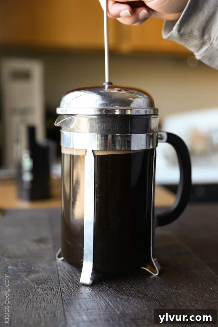 Unlock Barista-Quality French Press Coffee At Home 6 Hand plunging the French press slowly after 5-minute steep.