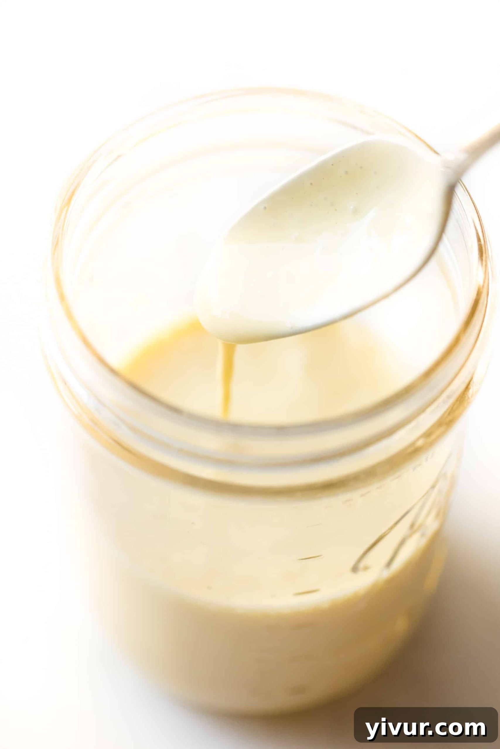 No-Fail Whole30 Hollandaise Sauce Paleo Keto Approved 2 Spoon pouring hollandaise sauce in a mason jar, showcasing its smooth texture