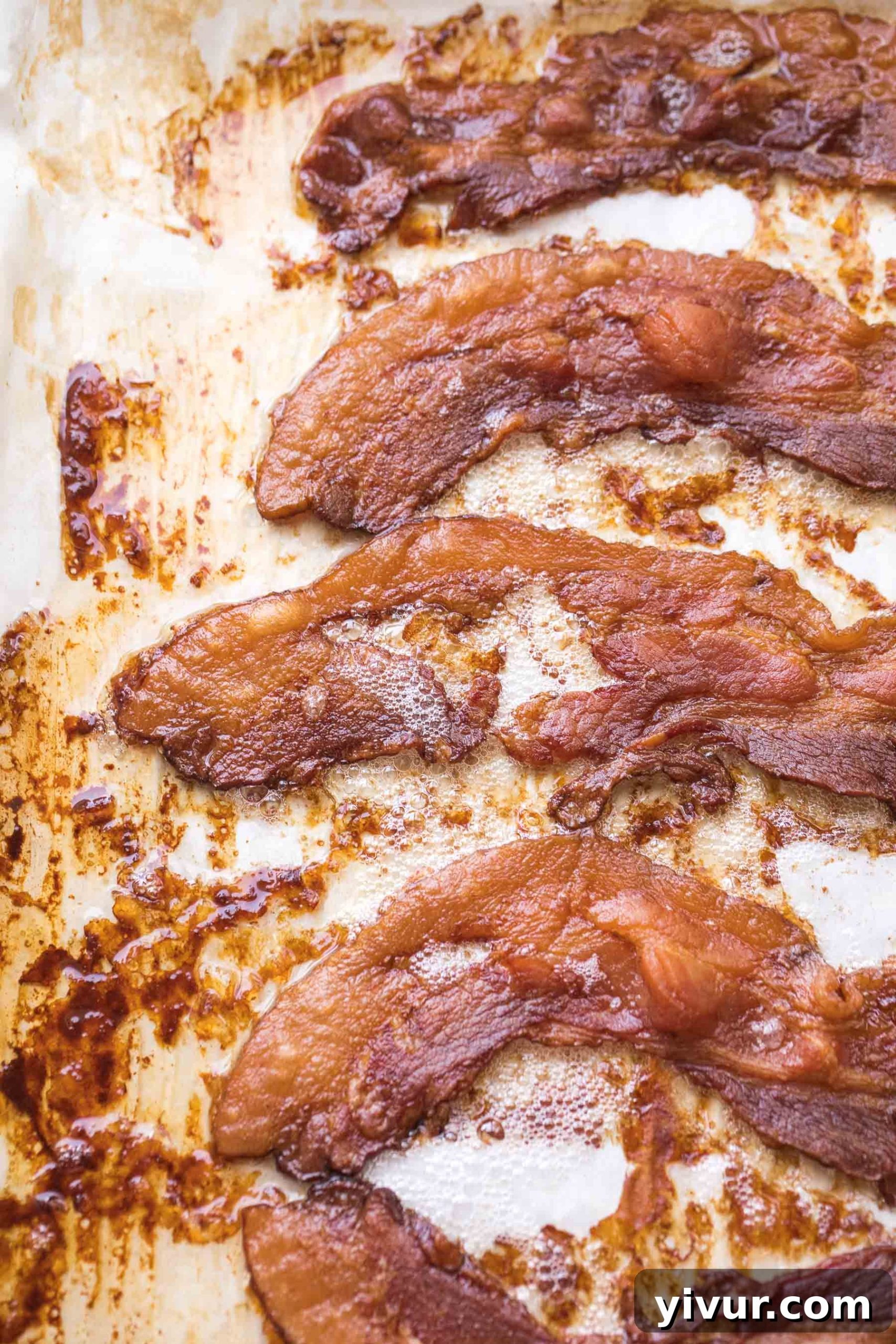 Perfectly crispy oven-baked bacon strips arranged on a white plate, ready to be served, highlighting the delicious outcome of the no-mess cooking method.