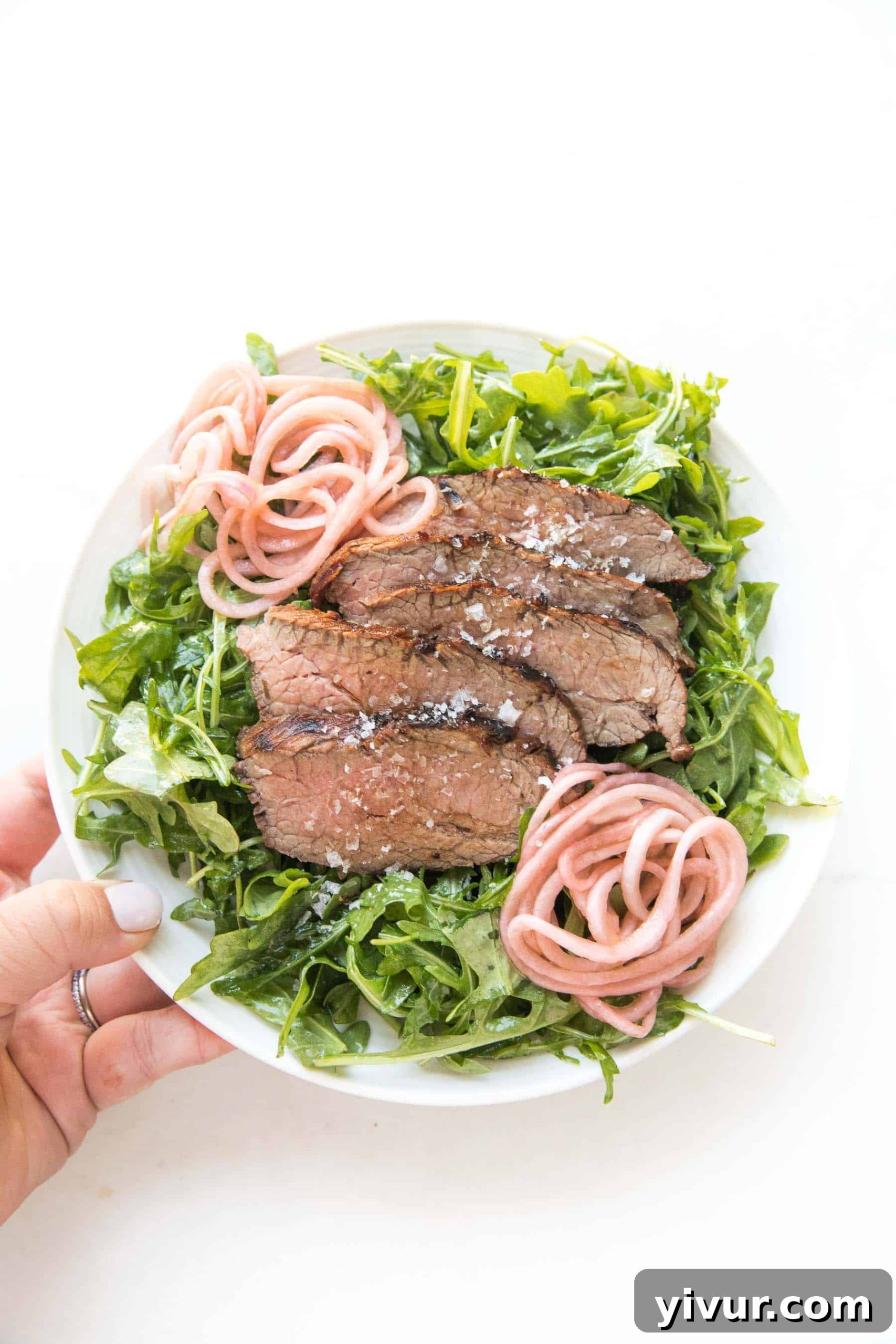 Savory Tri Tip Arugula Salad Whole30 Keto Paleo Approved 3 Hand holding a plate of Tri Tip Arugula Salad