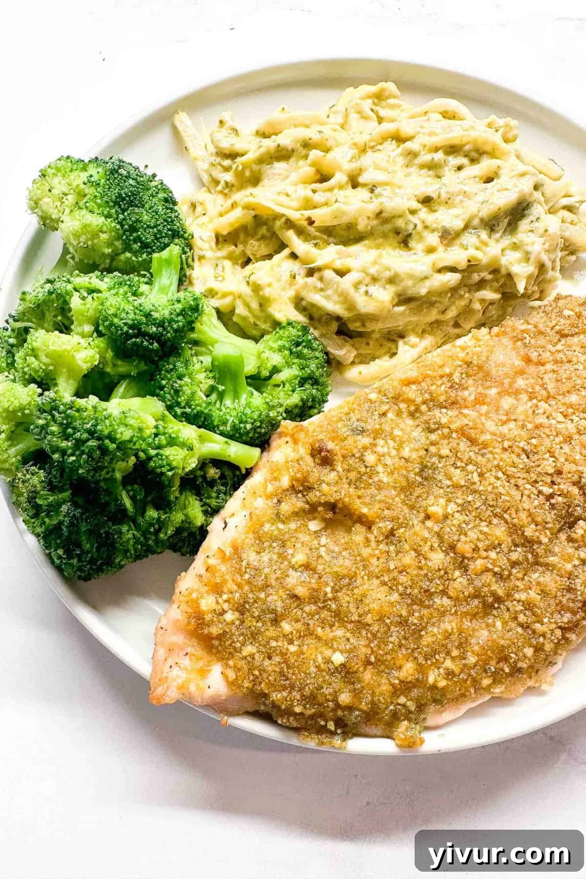 Crispy Baked Pesto Chicken served on a plate with vibrant broccoli and creamy mashed cauliflower, showcasing its golden crust and delicious appeal.