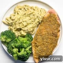 Crispy Baked Pesto Chicken served on a plate with vibrant broccoli and creamy mashed cauliflower, showcasing its golden crust and delicious appeal.