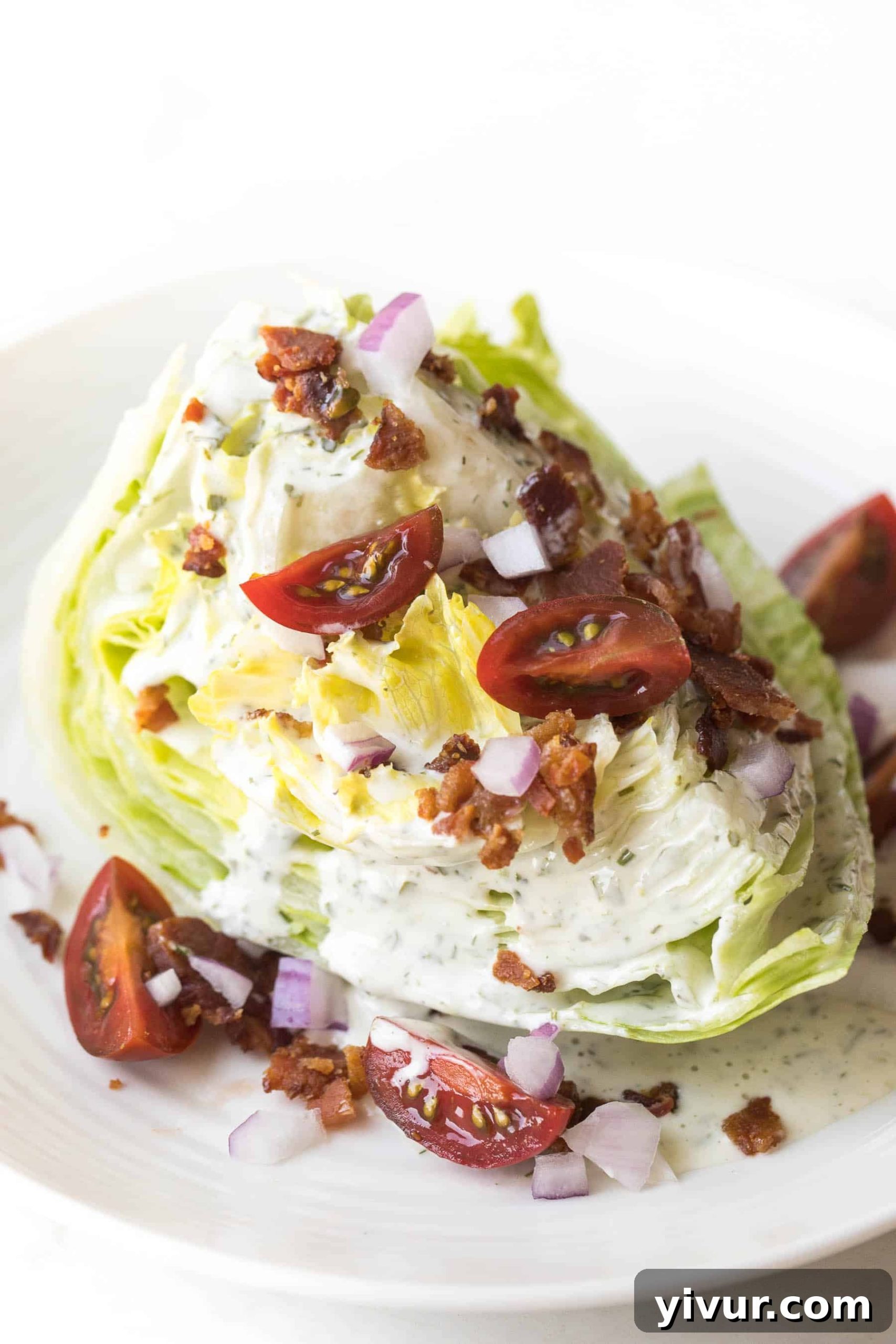 Classic Whole30 Keto Wedge Salad with dairy-free ranch, bacon, and tomatoes on a white plate