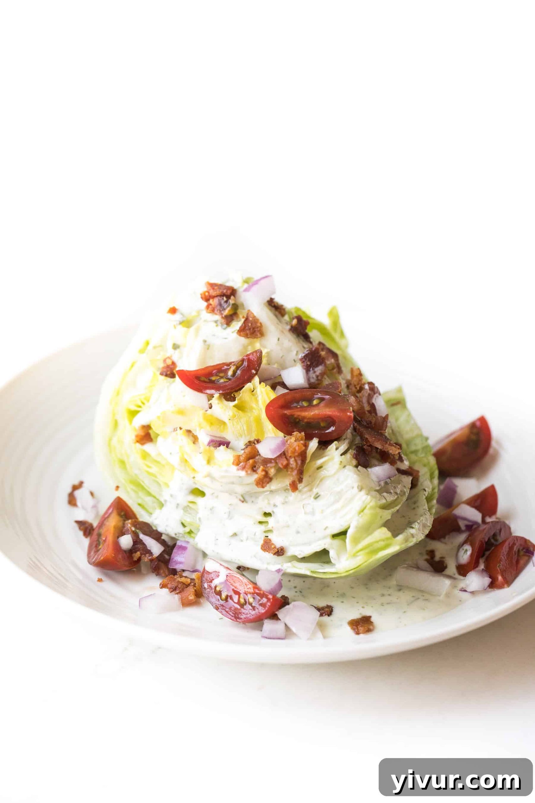 Whole30 Keto Wedge Salad ingredients artfully arranged with dressing, bacon, onion, and tomatoes