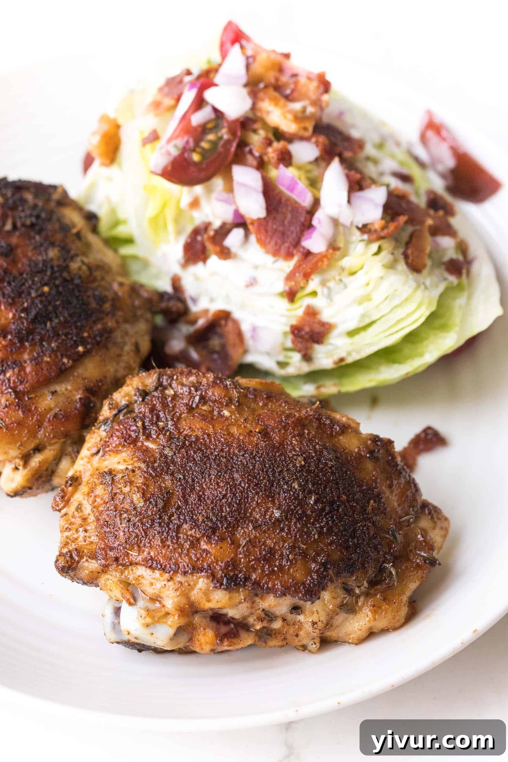cajun chicken thighs with a wedge salad on a white plate and white background