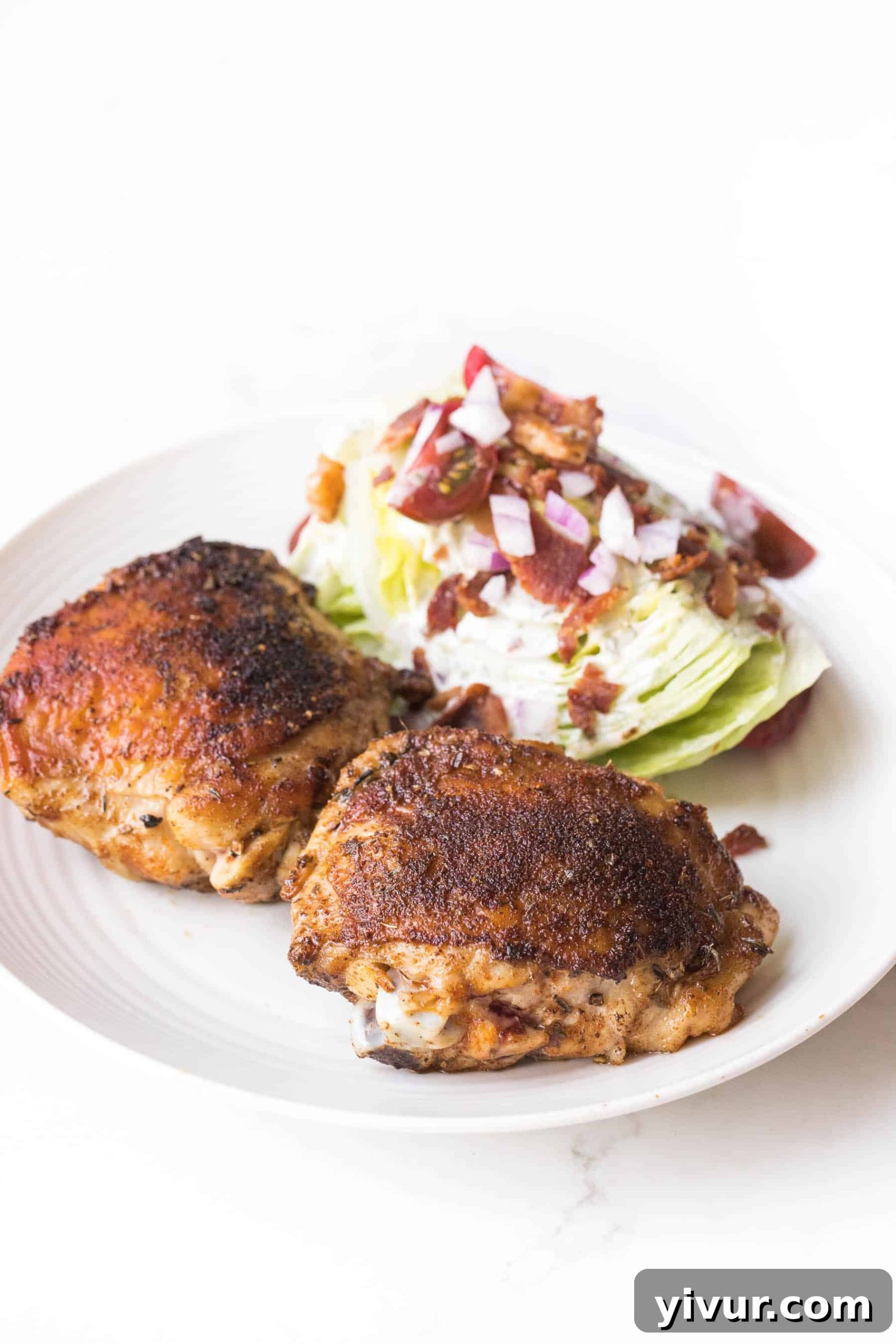 cajun chicken thighs with a wedge salad on a white plate and white background