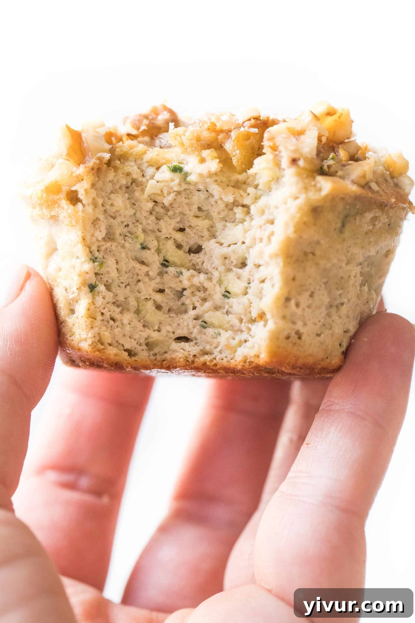 hand holding a paleo zucchini muffin on a white background