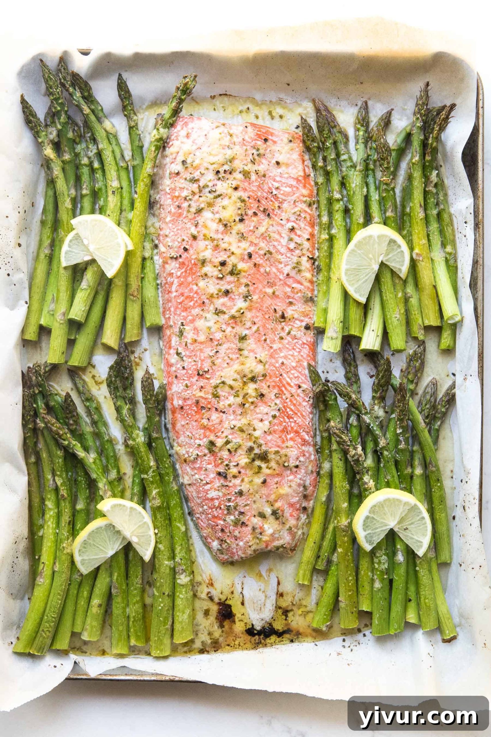 Sheet pan salmon and asparagus dinner with a vibrant green marinade poured over