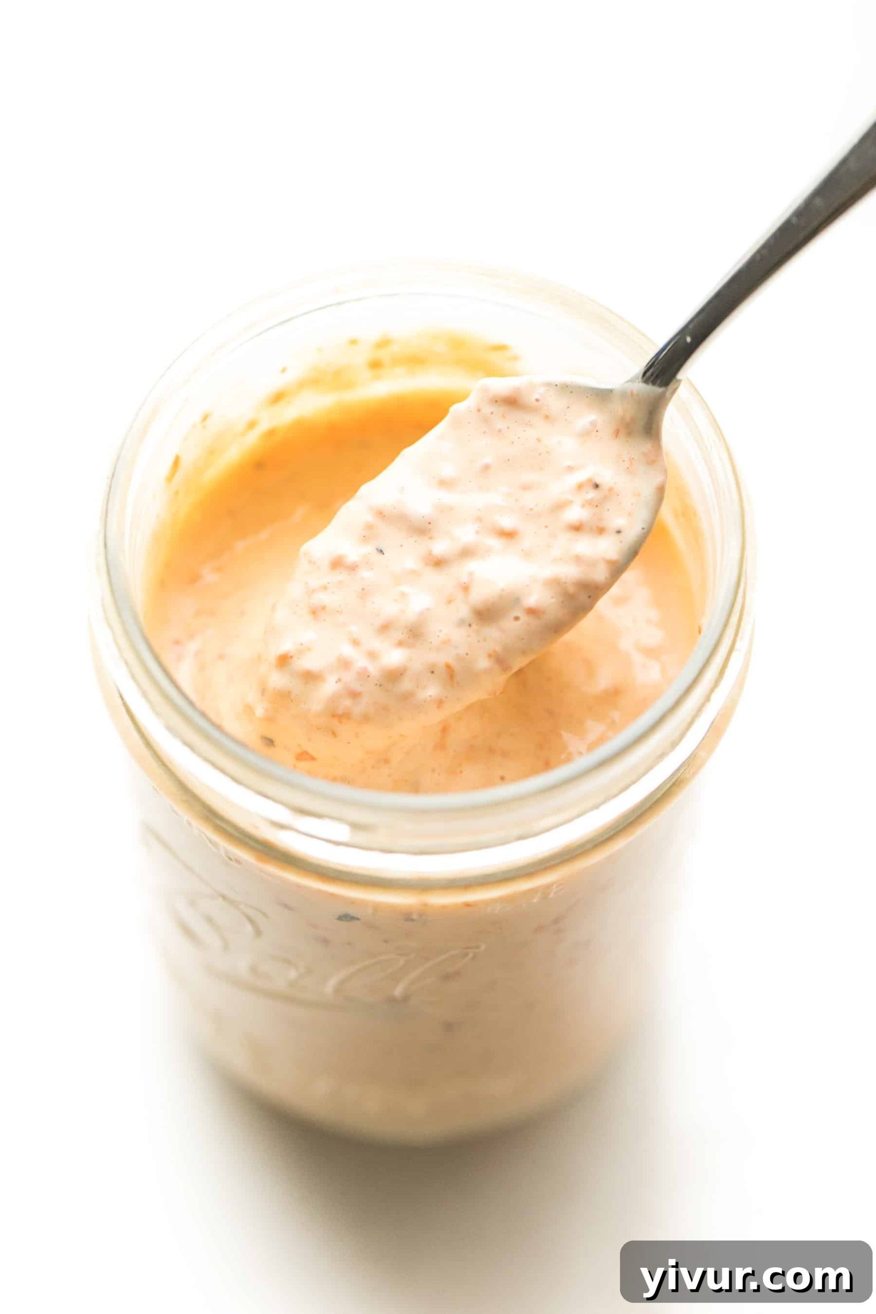 Spoon scooping out red pepper mayonnaise from a mason jar