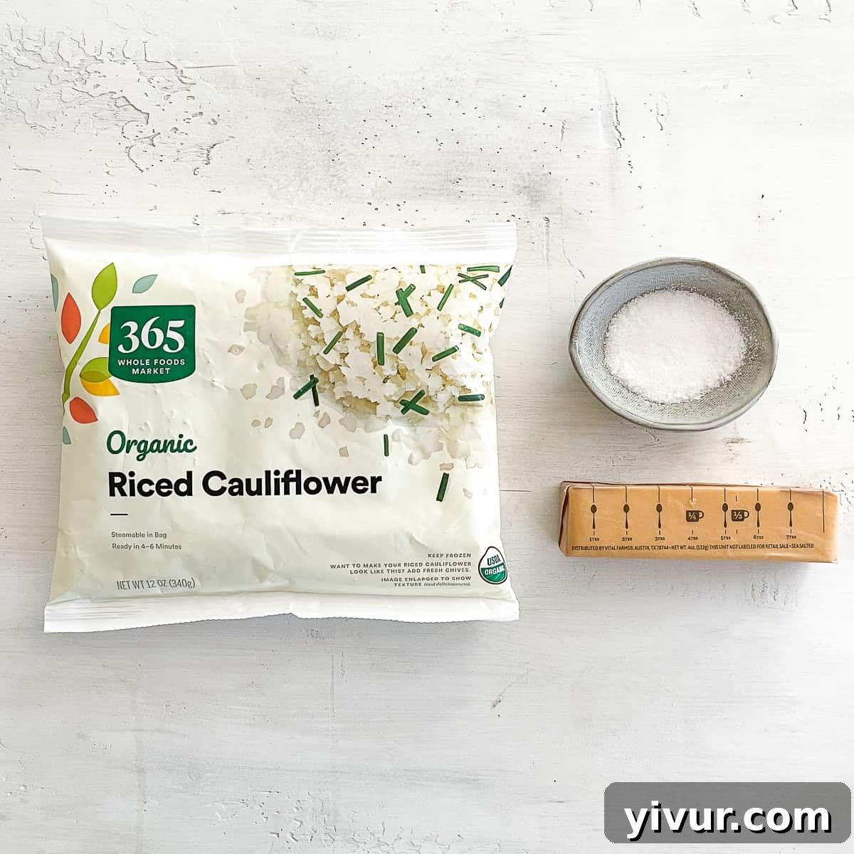 Quick and Easy Frozen Cauliflower Rice Hack 3 Ingredients laid out for preparing cauliflower rice: a bag of frozen cauliflower, olive oil, and salt.