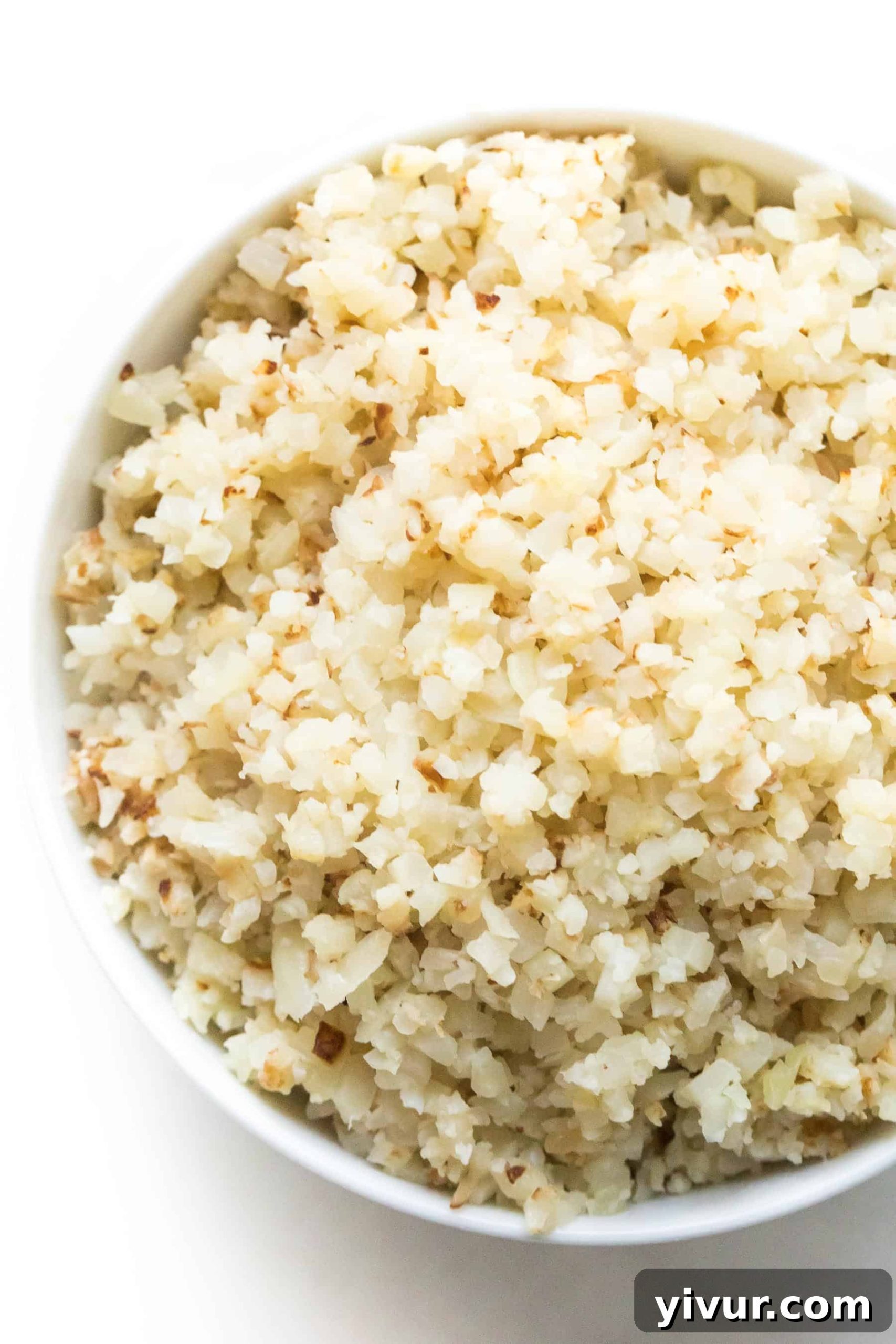 Quick and Easy Frozen Cauliflower Rice Hack 5 A serving of cooked cauliflower rice in a white bowl, garnished and ready for a meal.