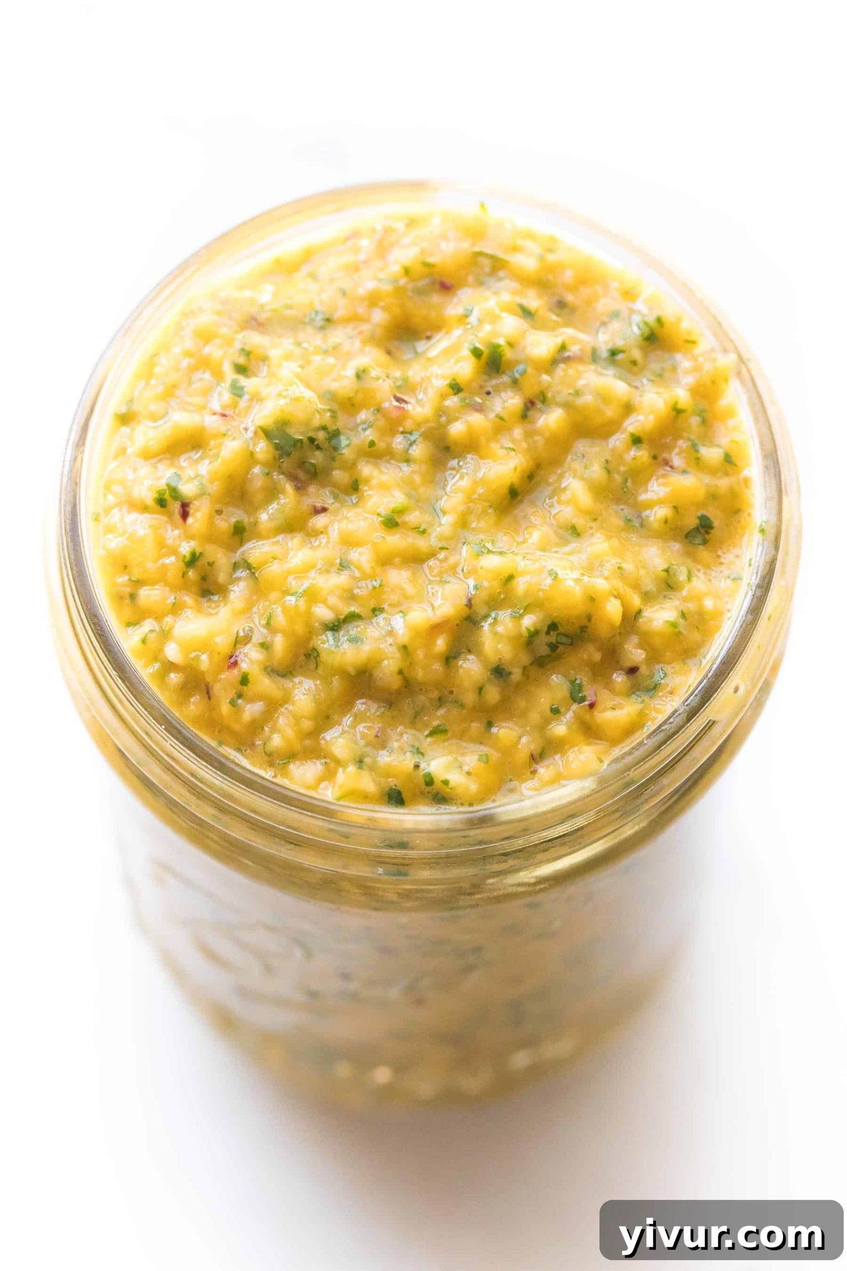 Vibrant mango salsa in a mason jar on a clean white background, garnished with fresh cilantro.