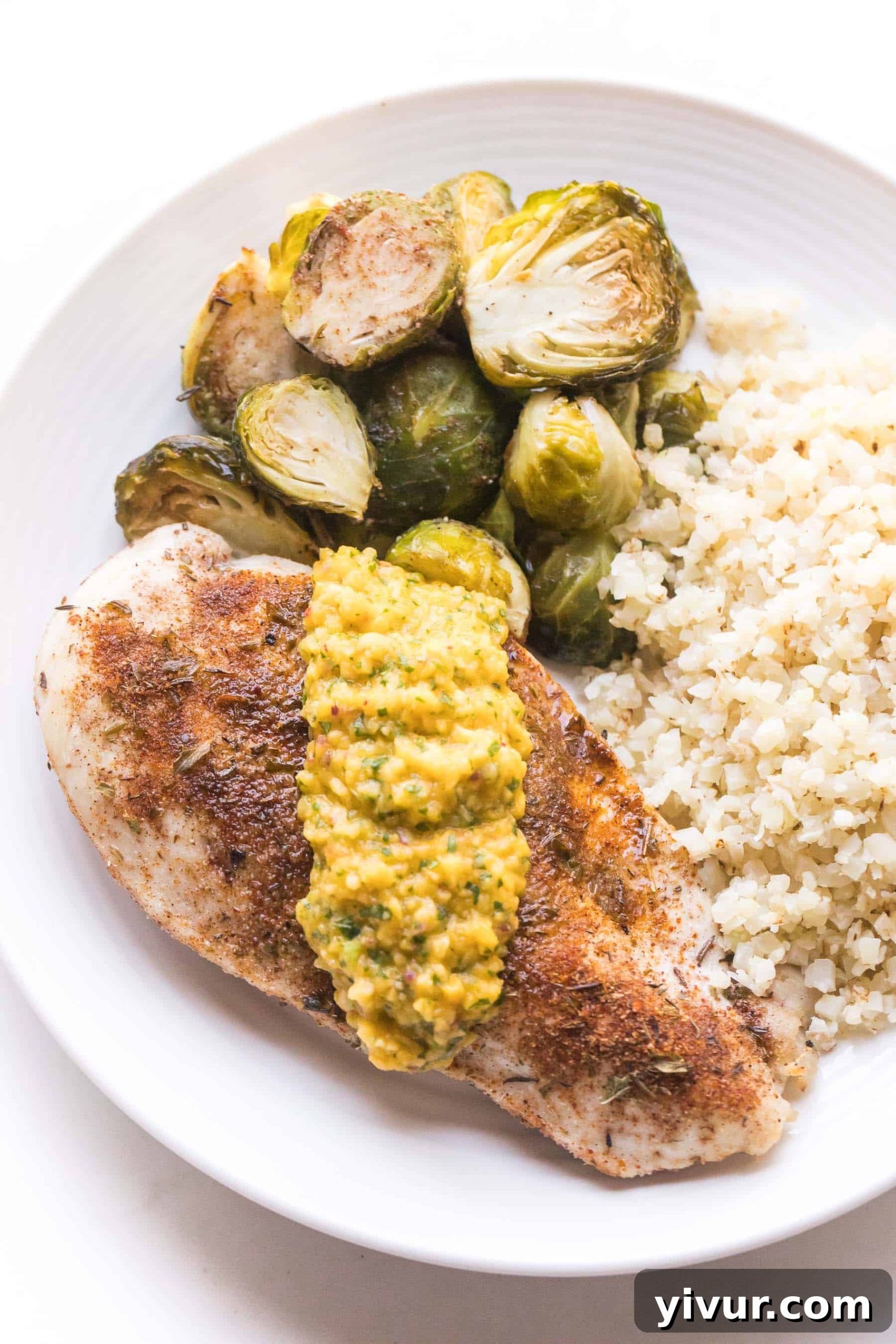 Jamaican Jerk Whole30 Keto Sheet Pan Chicken 3 jamaican chicken topped with mango salsa with brussles sprouts and cauliflower rice on a white plate