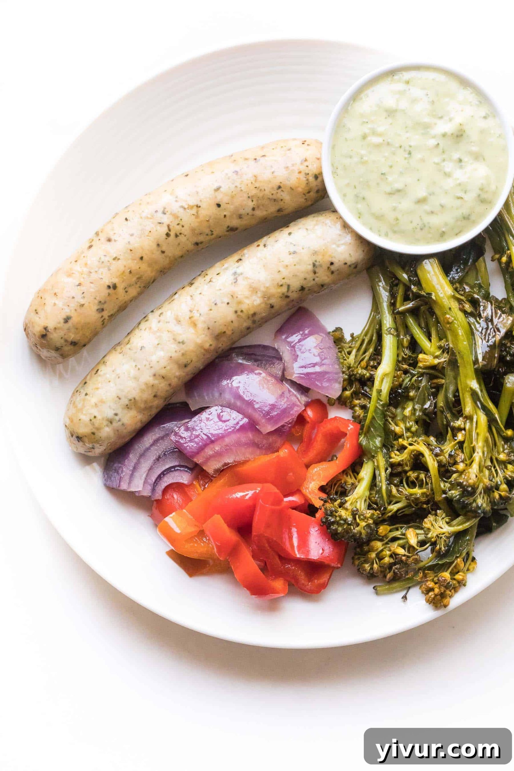 sausages and vegetables on a white plate on a white background