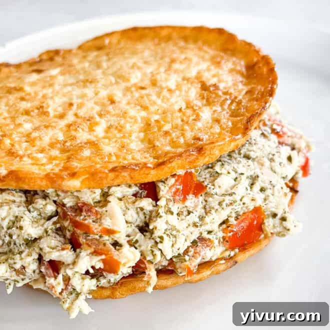 Keto pesto chicken salad on cauliflower thins on a white plate with a white background