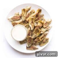 Roasted artichokes on a white plate with a white dip on a white background
