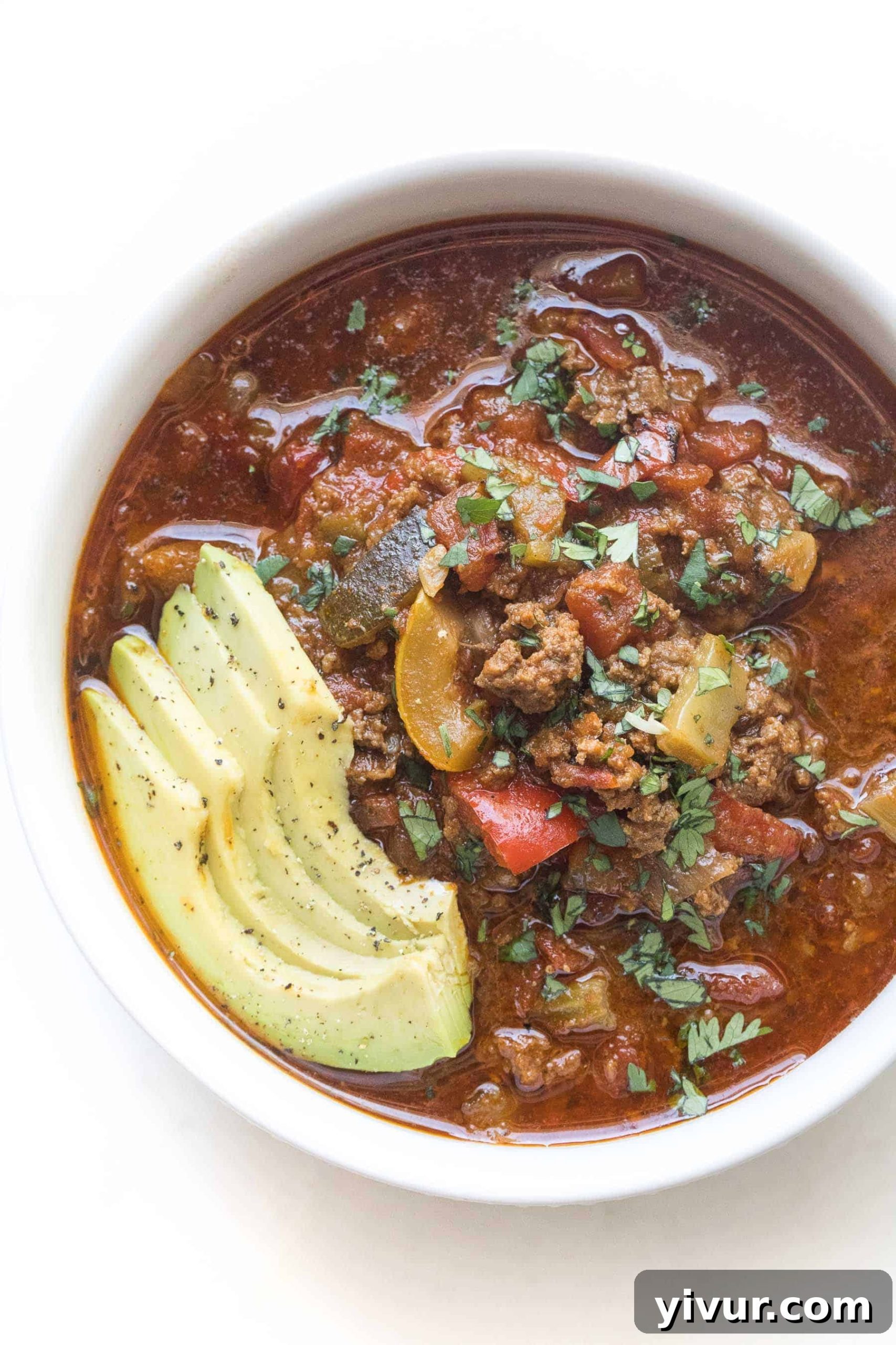 Keto Whole30 Instant Pot Chili Beanless and Easy 2 A vibrant bowl of Keto Instant Pot Chili, garnished with fresh avocado slices, chopped cilantro, and spicy jalapeños, showcasing its rich texture and appetizing colors.