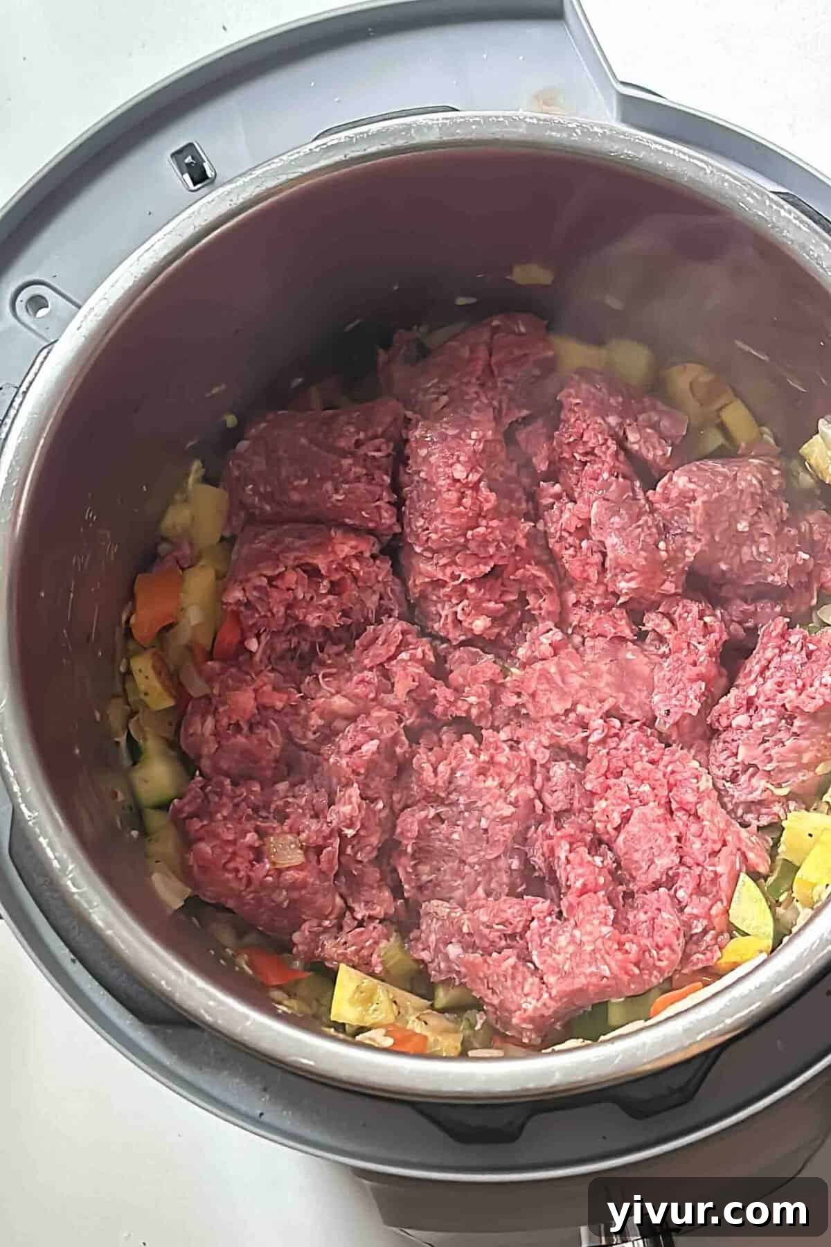 Keto Whole30 Instant Pot Chili Beanless and Easy 5 Ground beef browning and breaking up in an Instant Pot, mixed with already sautéed vegetables, preparing for the next stages of chili preparation.