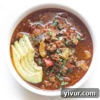 A comforting bowl of Keto Instant Pot Chili against a clean white background, garnished simply to highlight its appealing texture and color.