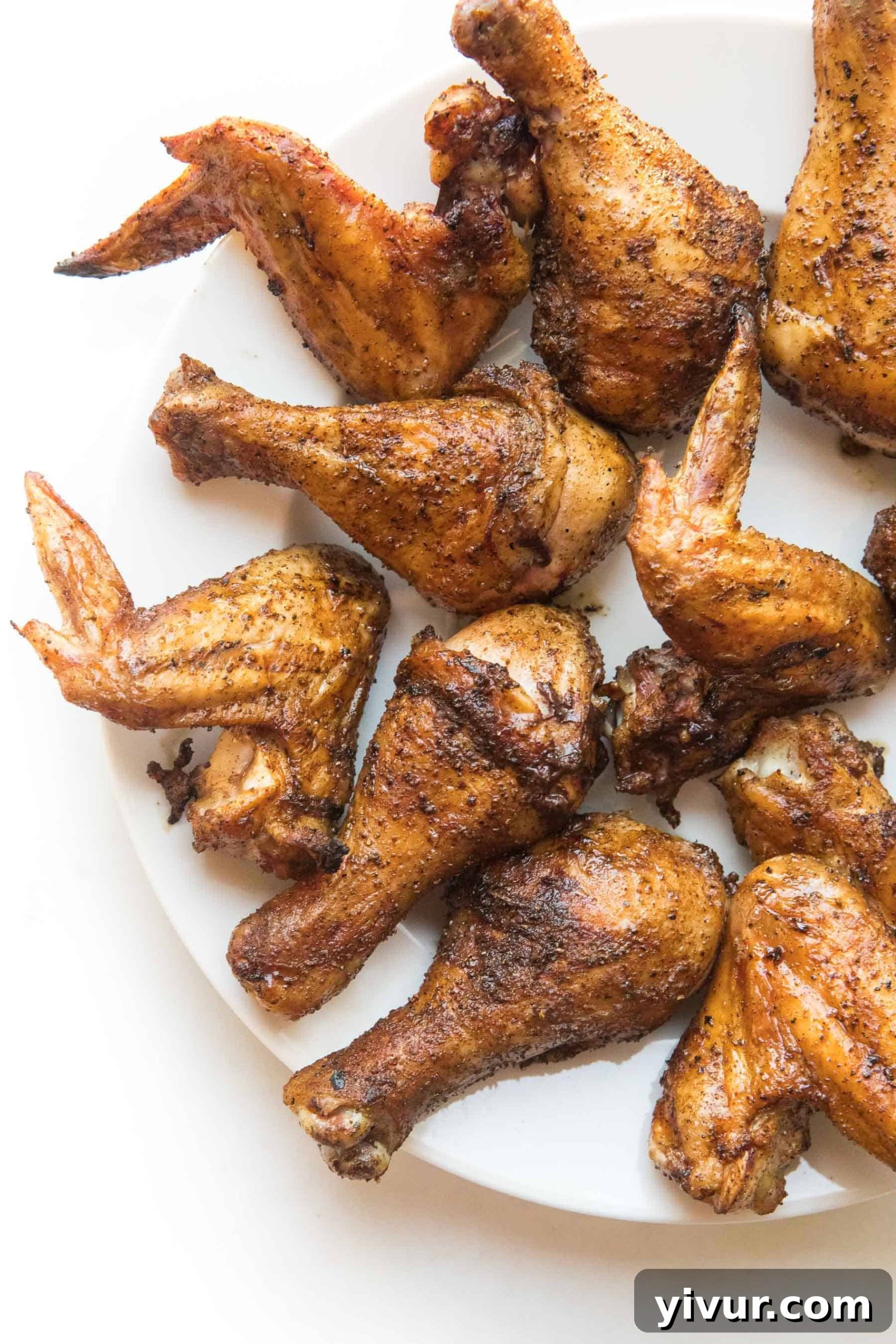 Golden Crispy Whole30 & Keto Chicken Drumsticks and Wings 2 crispy roasted drumsticks + wings on a white plate and background