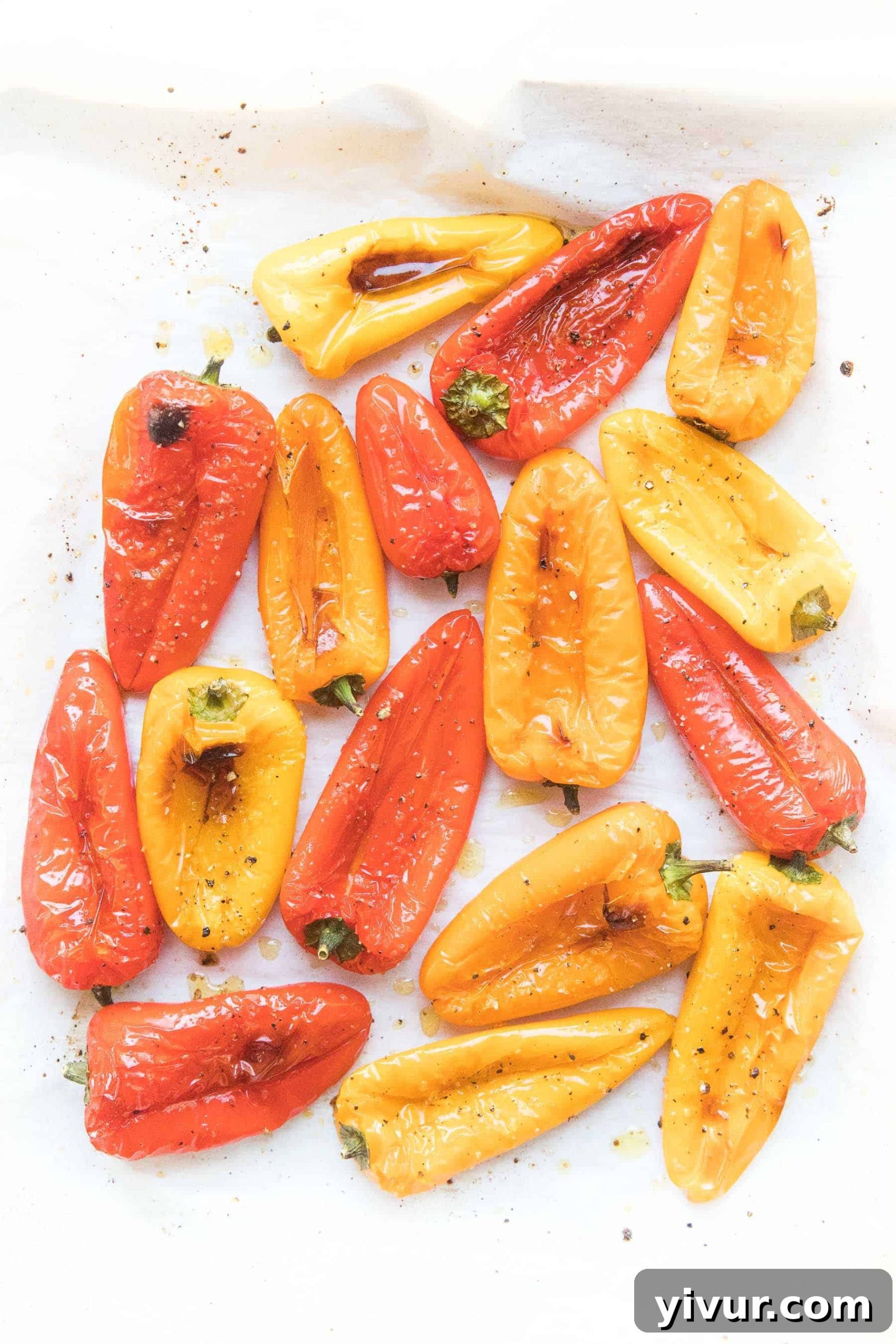 Roasted mini bell peppers with a slight char on parchment paper, illustrating perfect doneness