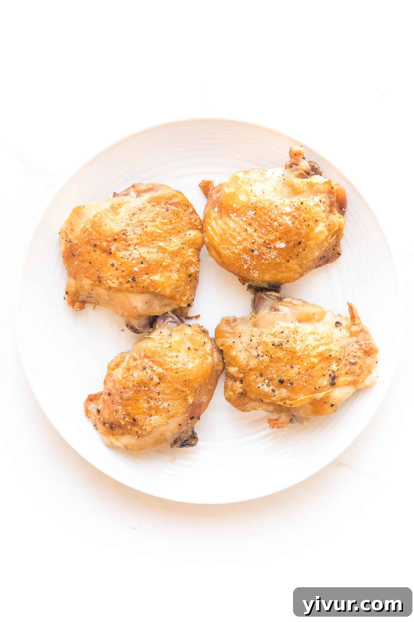 Plated crispy golden brown chicken thighs with a simple white background