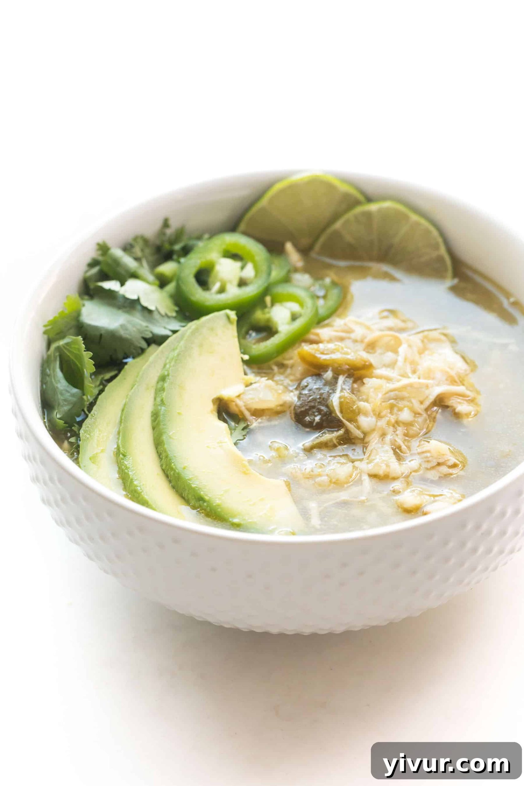 Effortless Whole30 Keto Instant Pot Verde Chicken Chili 5 A beautifully presented bowl of green Verde Chicken Chili, ready to be served. The chili is garnished with fresh herbs and a lime wedge, highlighting its vibrant appearance and appeal as a healthy, low-carb meal.