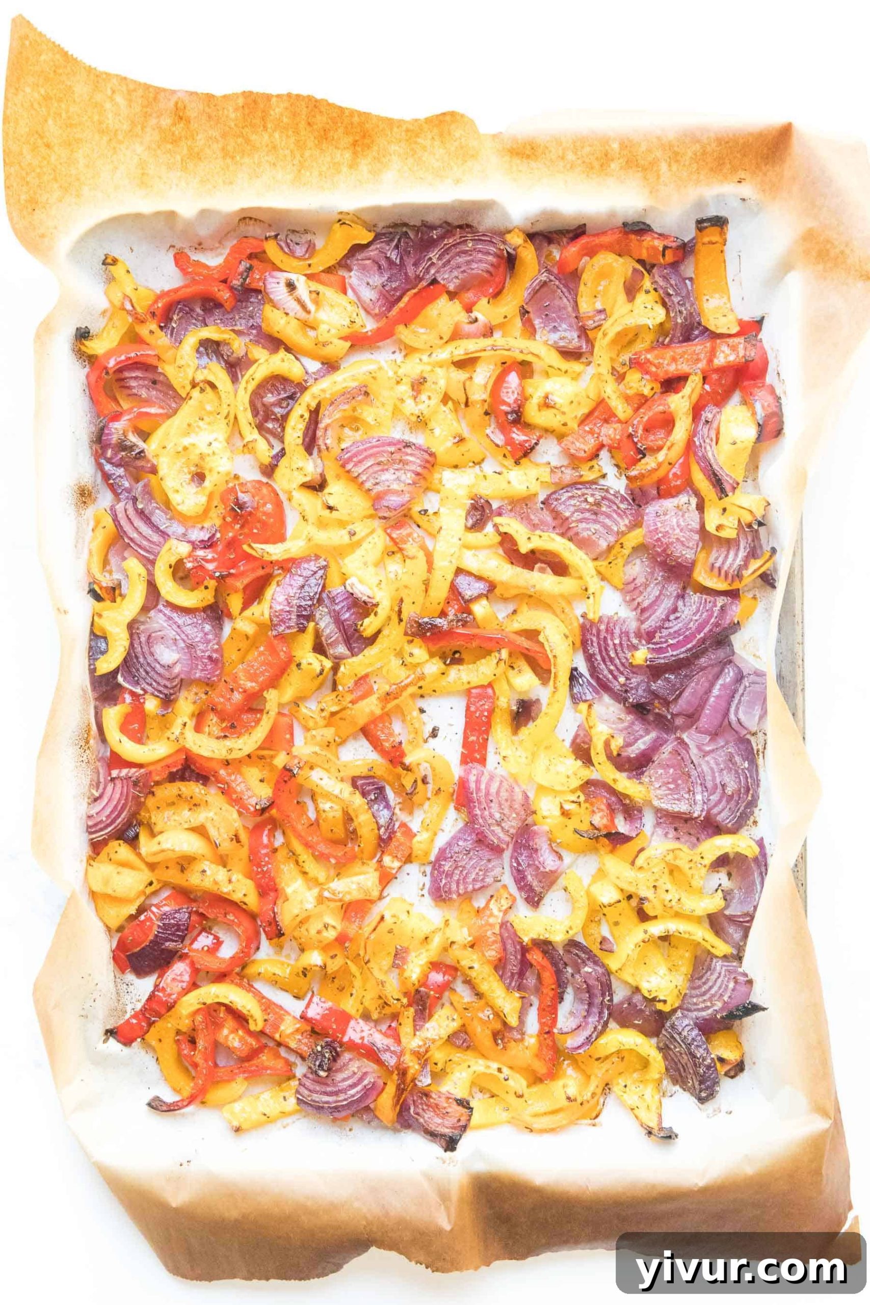 Close-up of perfectly roasted bell pepper and onion fajita veggies on a sheet pan, showing tender texture and charred edges