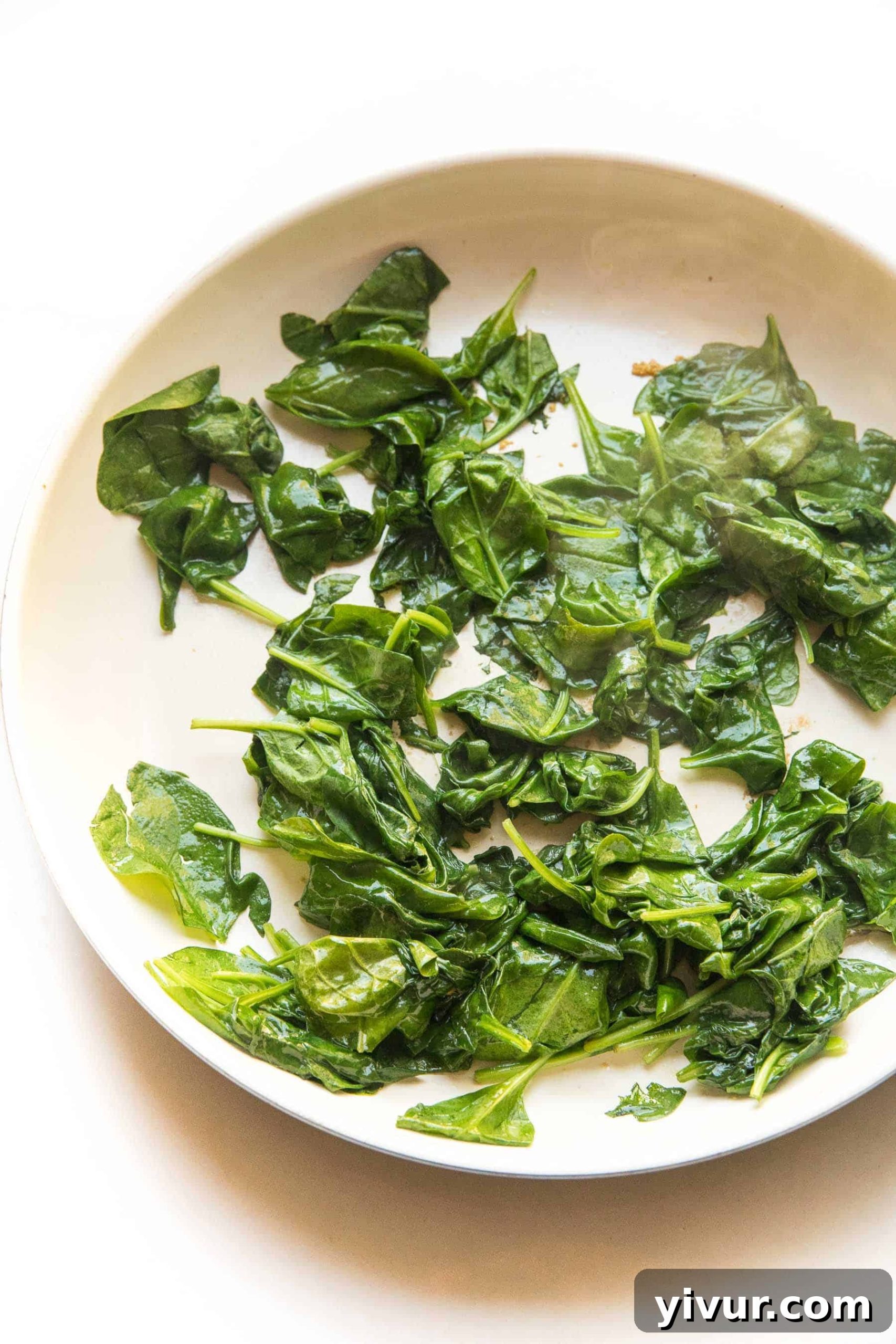Sautéed spinach served in a white skillet, ready to be enjoyed.