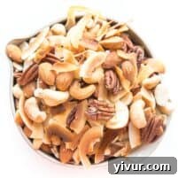 nuts and coconut chips trail mix in a bowl on white background