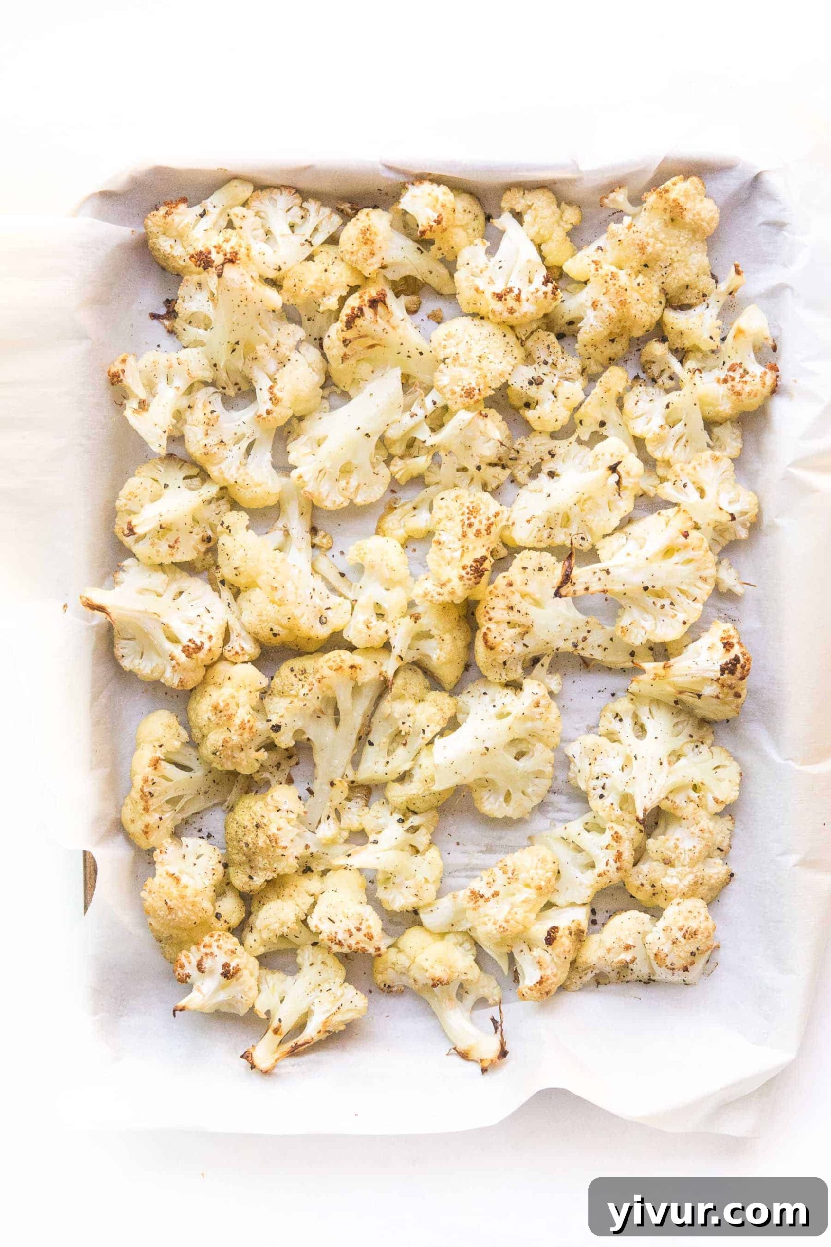 Roasted cauliflower with golden, crispy edges on a sheet pan, ready to serve.
