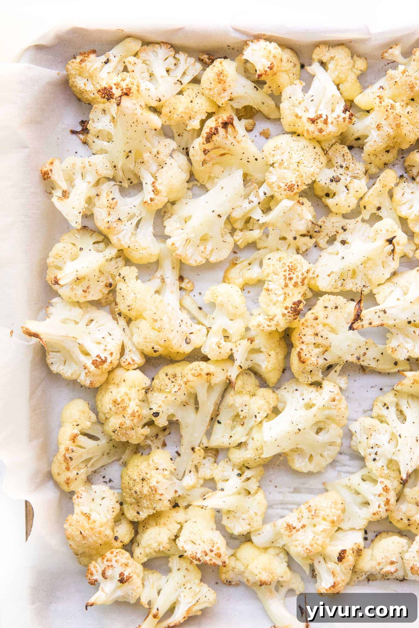 Close-up shot of perfectly roasted cauliflower florets on a baking sheet, showcasing crispy texture.