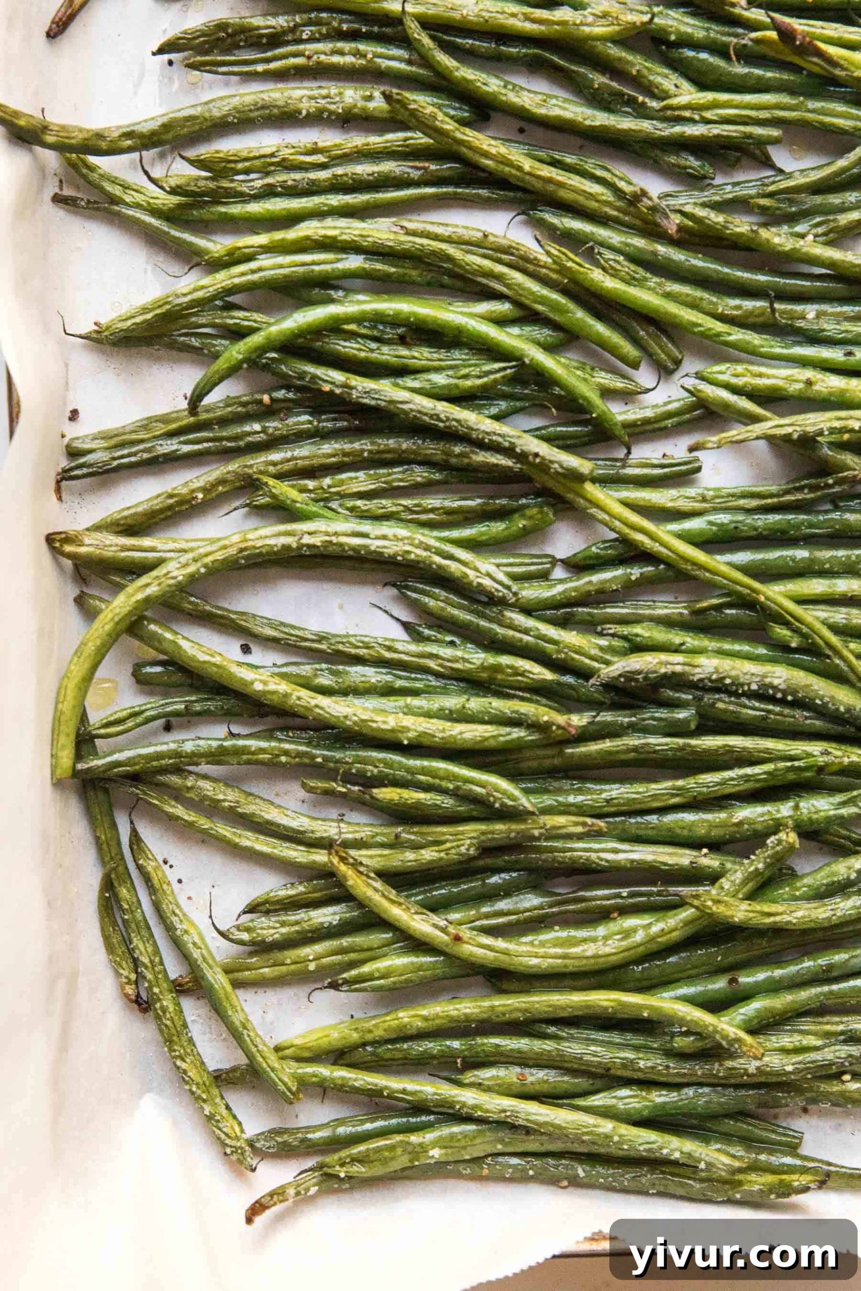 Close-up of golden-brown roasted green beans on a baking sheet, ready to serve
