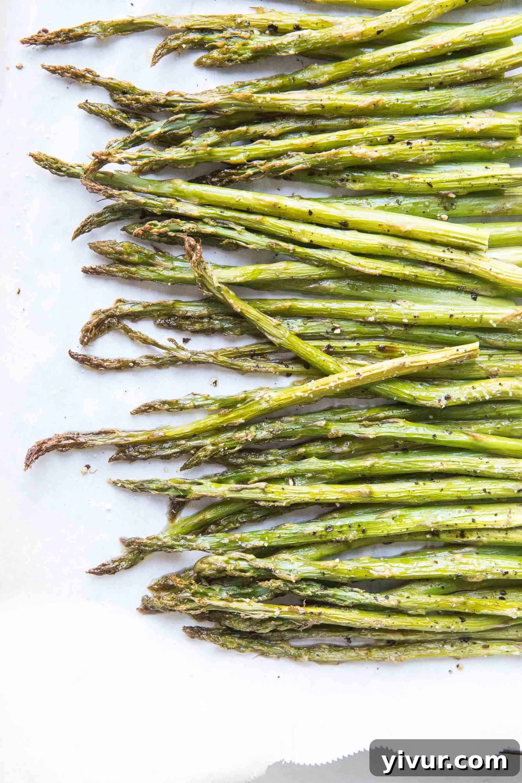 Close-up of roasted asparagus spears on a baking sheet, showing crispy ends