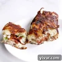 A white plate holds two pieces of a crispy, golden-brown stuffed dish with visible bacon, green onions, and crispy potato. One piece is whole, while the other is cut open to reveal the hearty filling—perfect for a high protein breakfast.